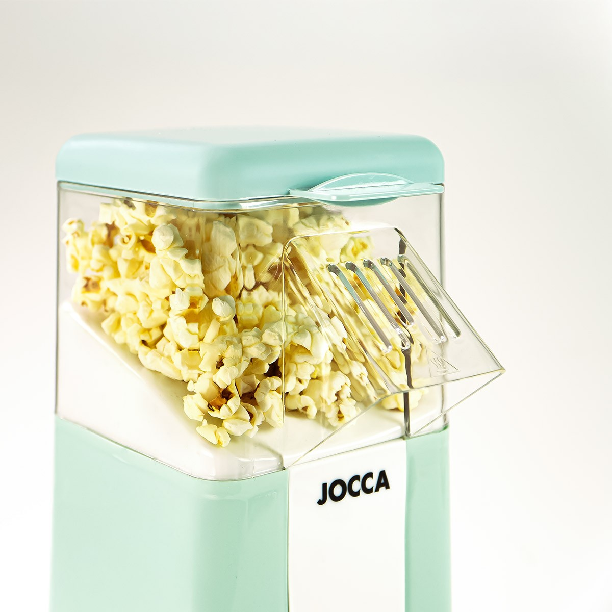 Una macchina per popcorn verde menta con popcorn all'interno. La macchina ha un contenitore trasparente. La parola JOCCA è visibile.