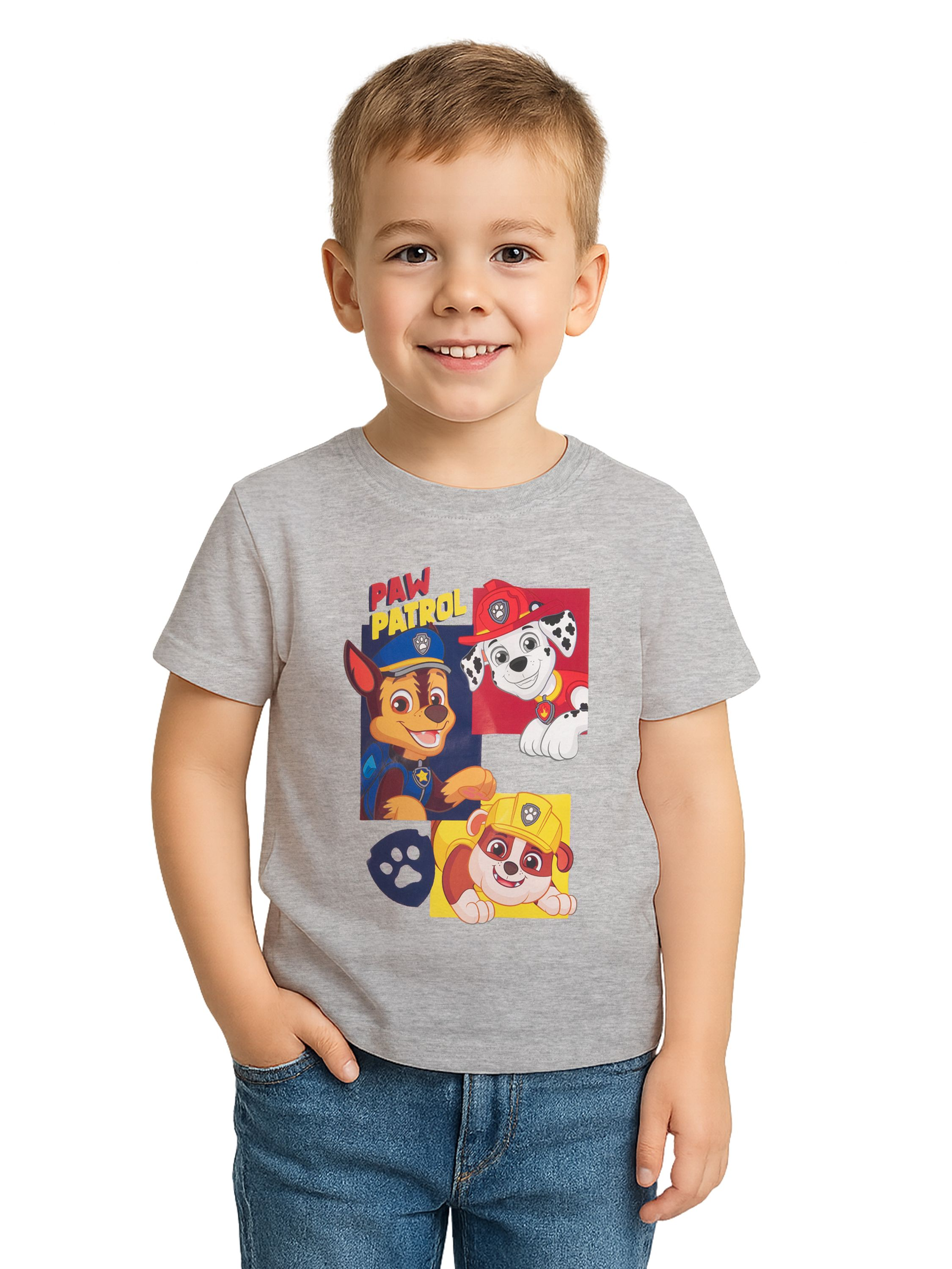 Ein lächelnder Junge in einem grauen Shirt mit Paw Patrol-Design, Jeans und Hand in der Tasche.