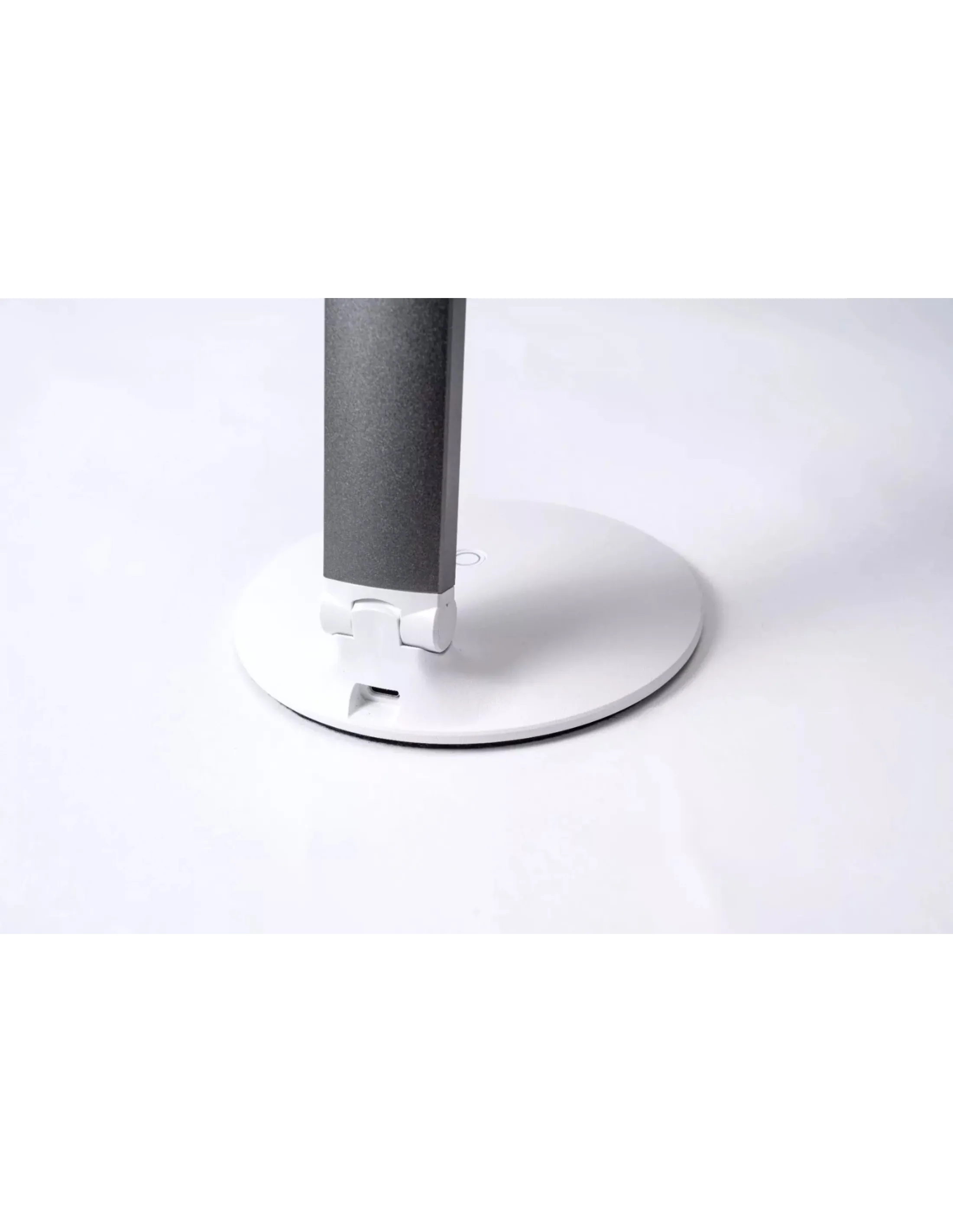 Een moderne bureaulamp met een grijze steel en witte cirkelvormige voet.