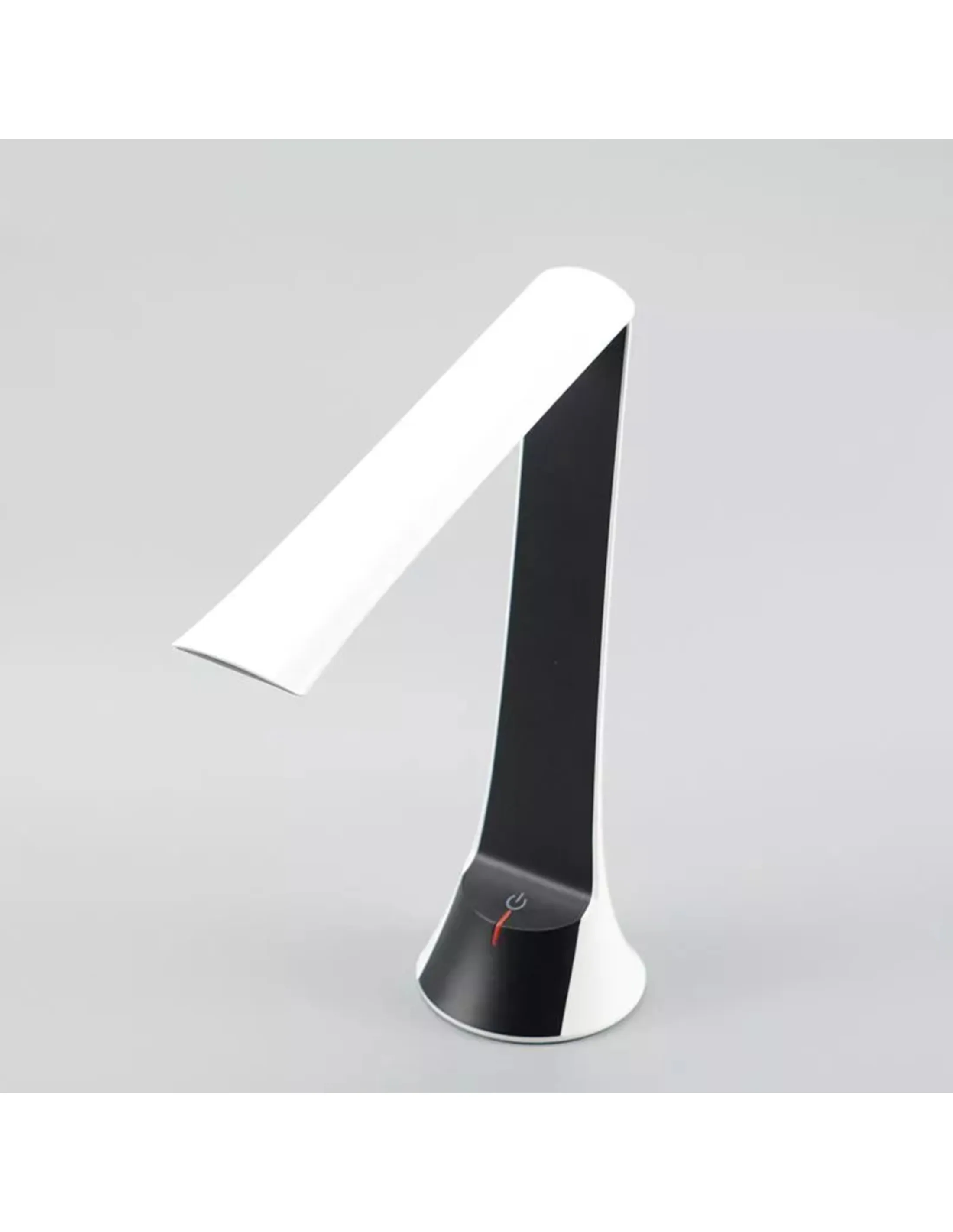 Een wit-zwarte bureaulamp op een grijze achtergrond. Hij staat uit. De lamp staat schuin.