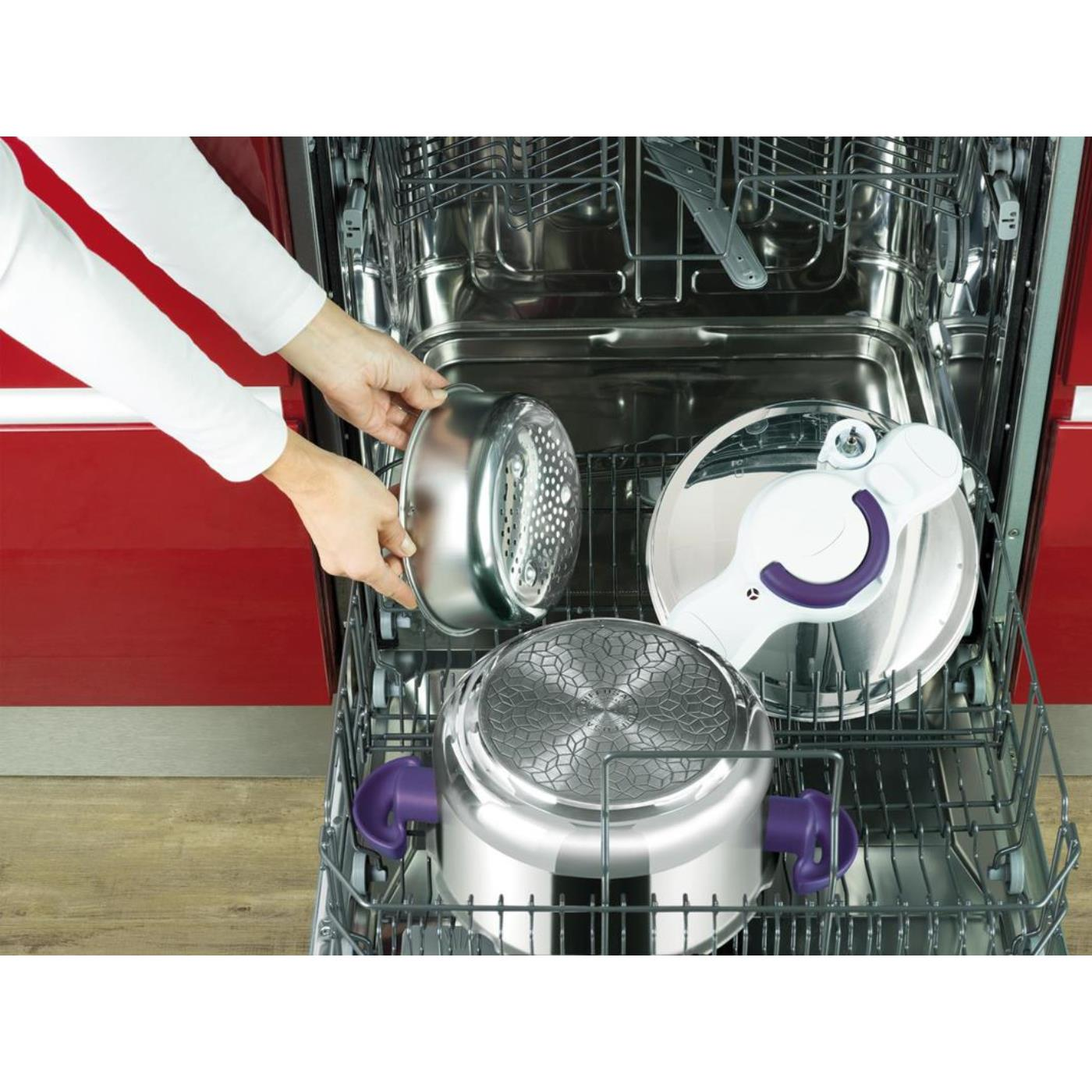 Eller, bir bulaşık makinesine metal bir süzgeç yerleştiriyor. Tencere ve kapak gibi diğer mutfak eşyaları içinde. Arka planda kırmızı dolap.