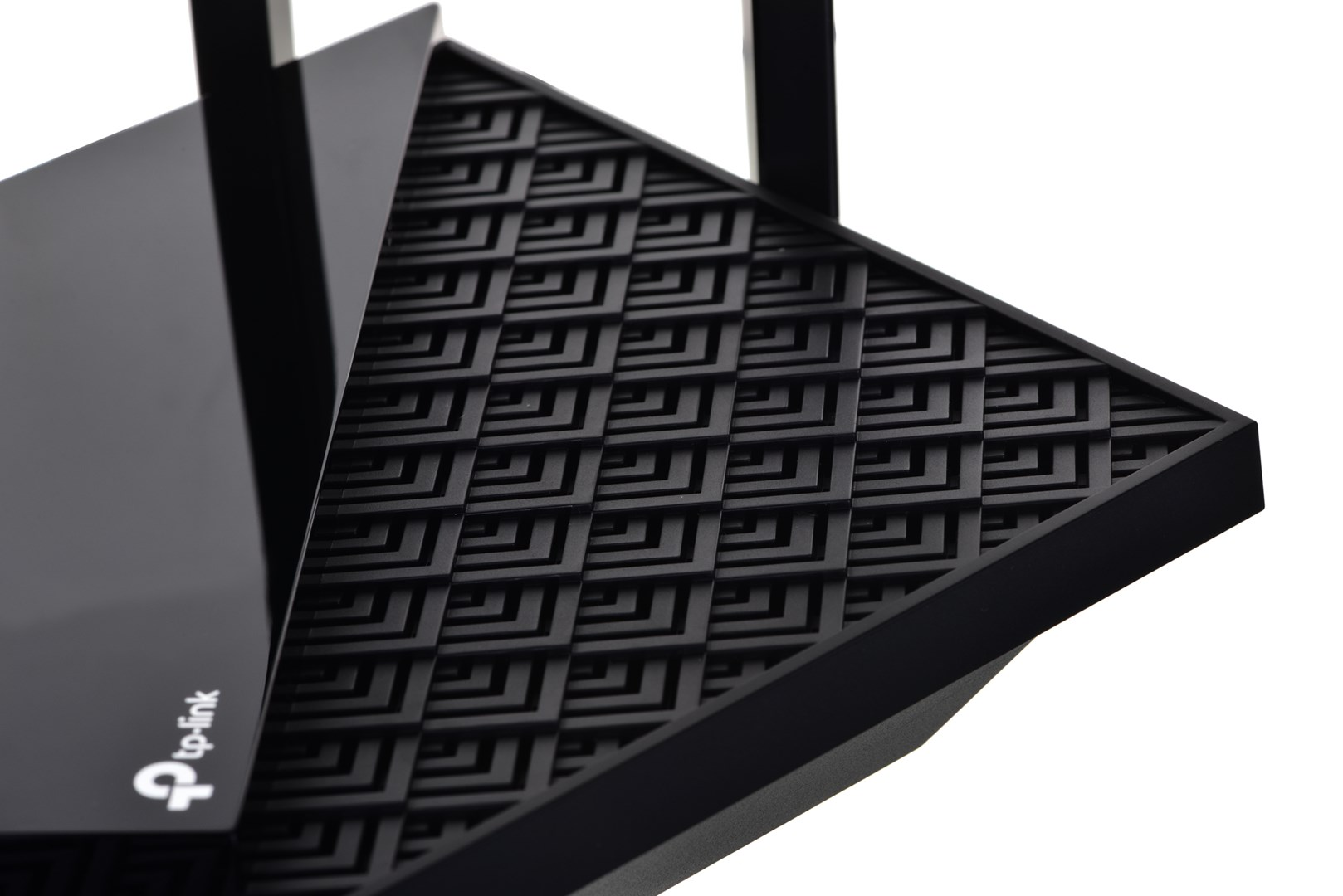 Zbliżenie czarnego routera z geometrycznym wzorem na górze. Widoczne logo tp-link. Anteny i błyszcząca strona obecne.