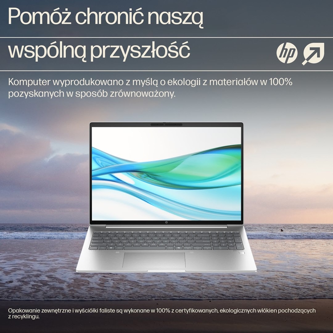 Srebrny laptop na plaży, z ekranem pokazującym zielone i niebieskie fale. Tło przedstawia ocean i zachód słońca.