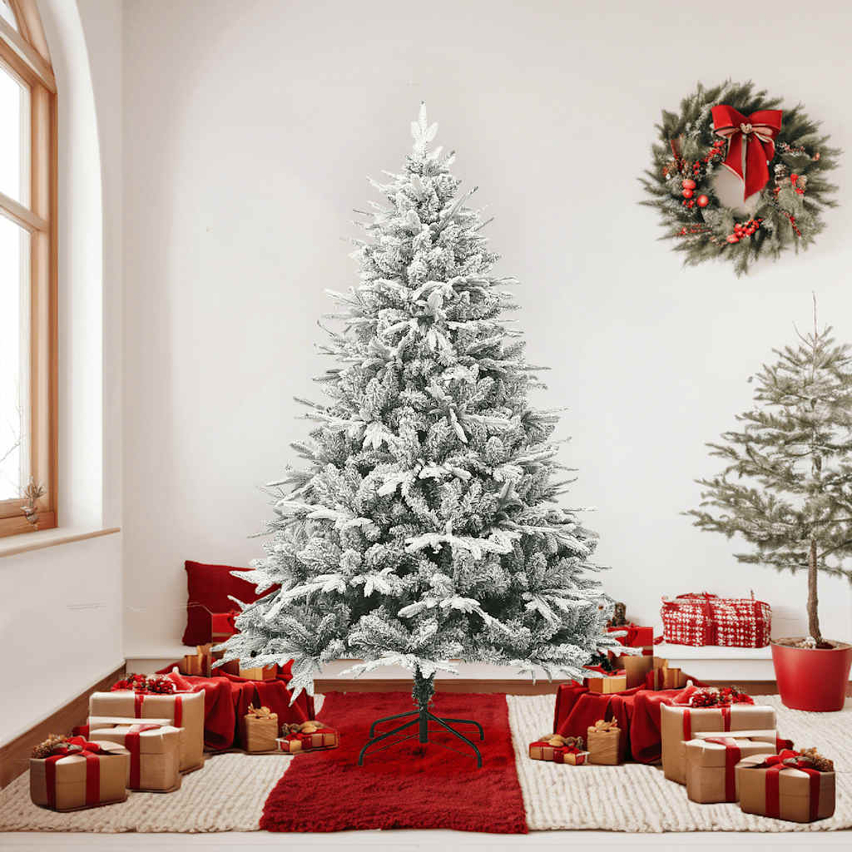 Eine dekorierte Weihnachtsszene. Ein schneebedeckter Baum steht auf einem roten Teppich, umgeben von Geschenken. Eine Girlande hängt an der Wand.