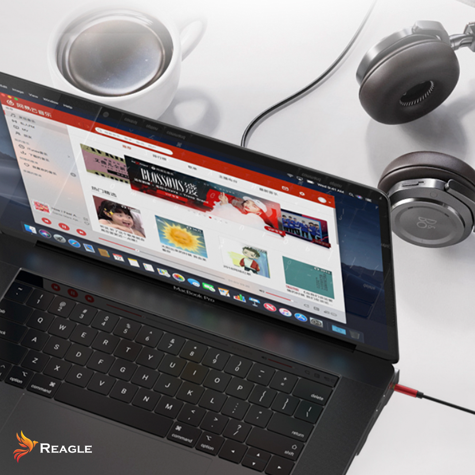 Laptop z otwartą stroną muzyczną, słuchawkami i filiżanką na białej powierzchni. Podłączony czerwony kabel.