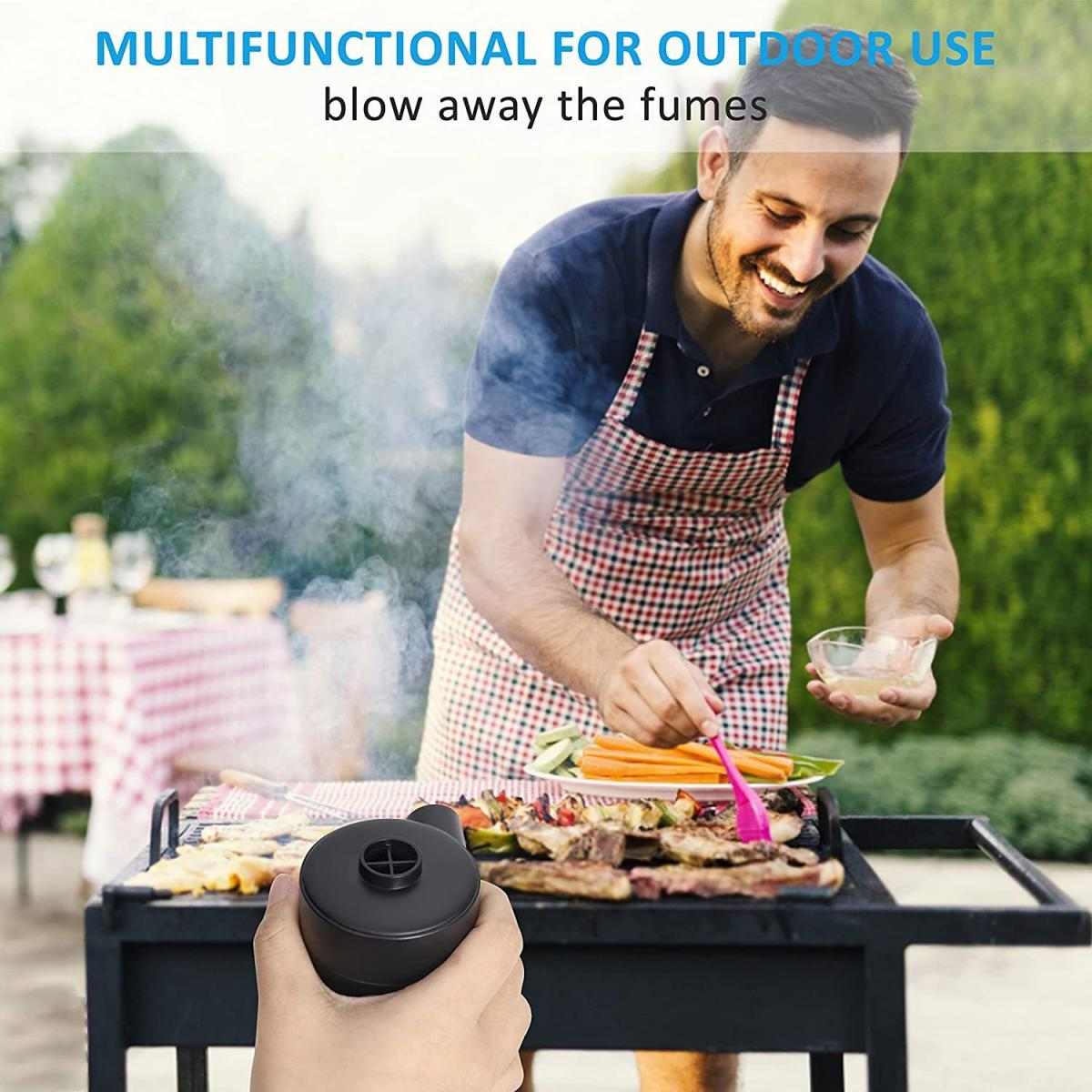 Mann grillt Essen. Er benutzt einen rosa Pinsel. Rauch steigt vom Grill auf. Ein schwarzes Gebläse ist im Vordergrund, wird von einer Hand gehalten.