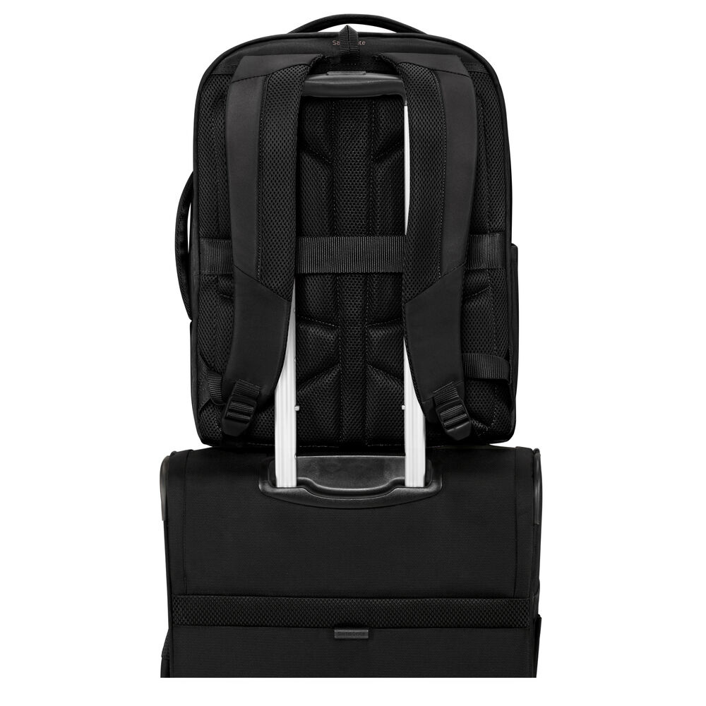 Schwarzer Rucksack auf einem schwarzen Koffer. Der Rucksack hat einen Griff und Träger. Der Koffer hat einen ausgezogenen Griff.