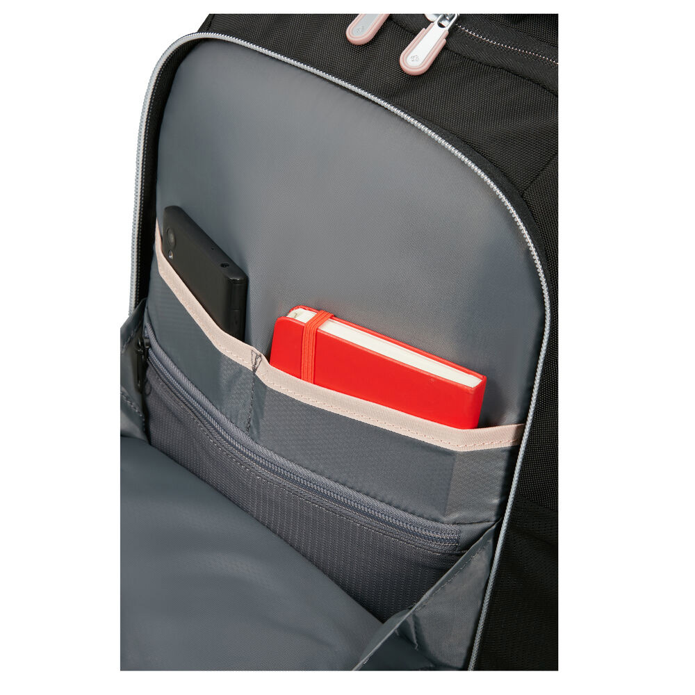 In einem schwarzen Rucksack befinden sich ein rotes Notizbuch, ein schwarzes Telefon und ein graues Futter. Reißverschlüsse und hellrosa Akzente sind sichtbar.