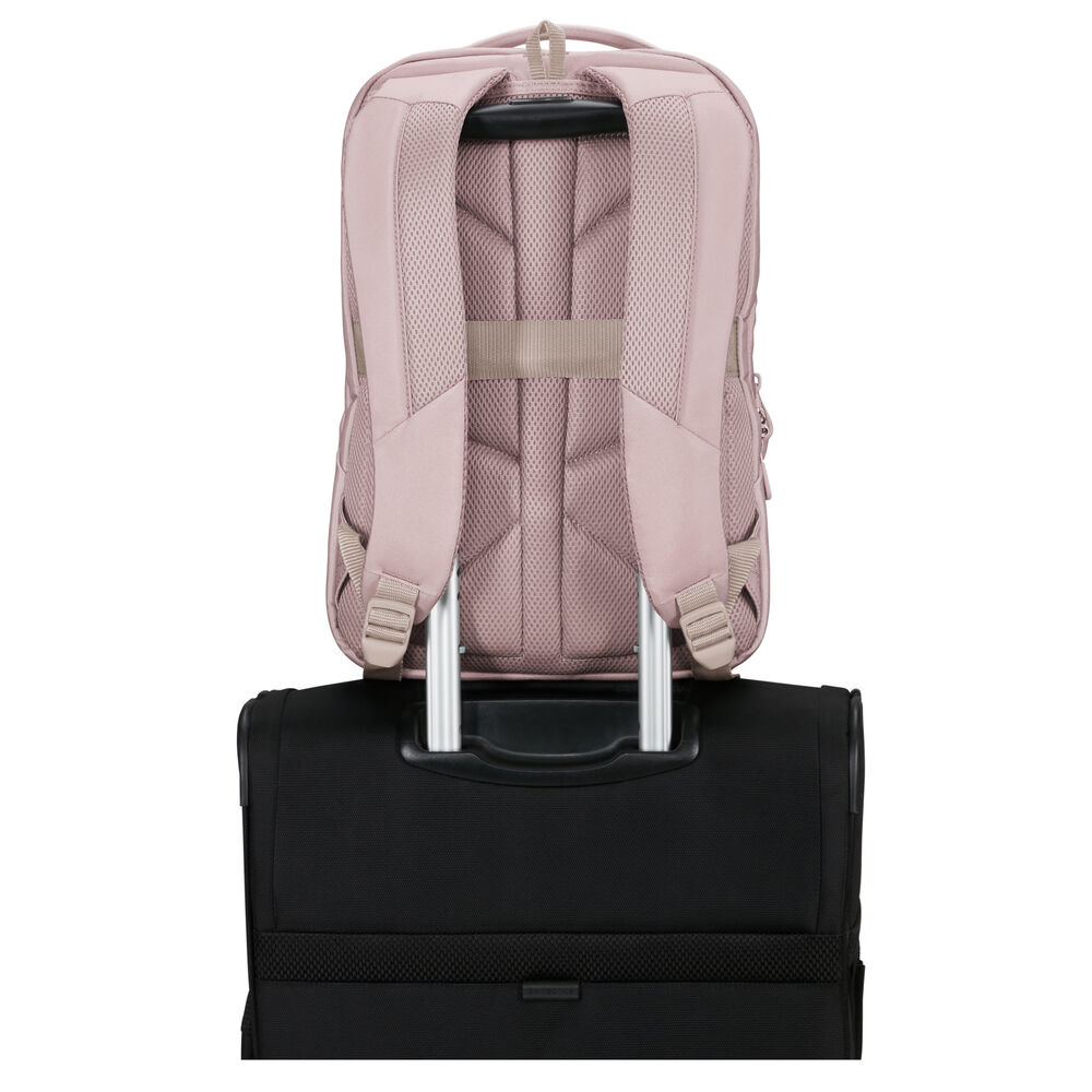 Ein rosa Rucksack steht auf einem schwarzen Rollkoffer. Der Rucksack hat gepolsterte Gurte, und der Koffergriff ist sichtbar.