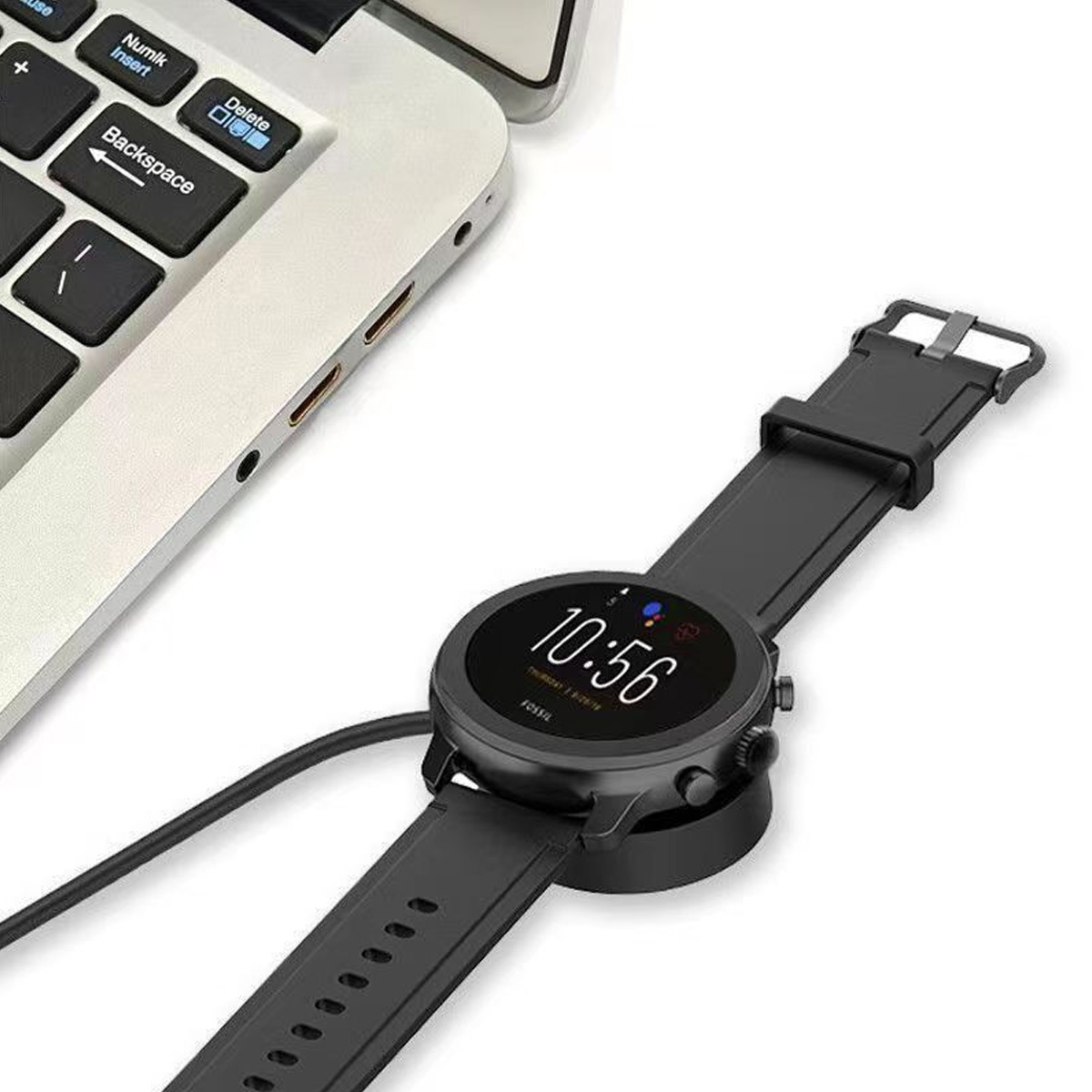 Schwarze Fossil-Smartwatch, die geladen wird und 10:56 anzeigt. Sie liegt neben einem Laptop auf einem Ladegerät.