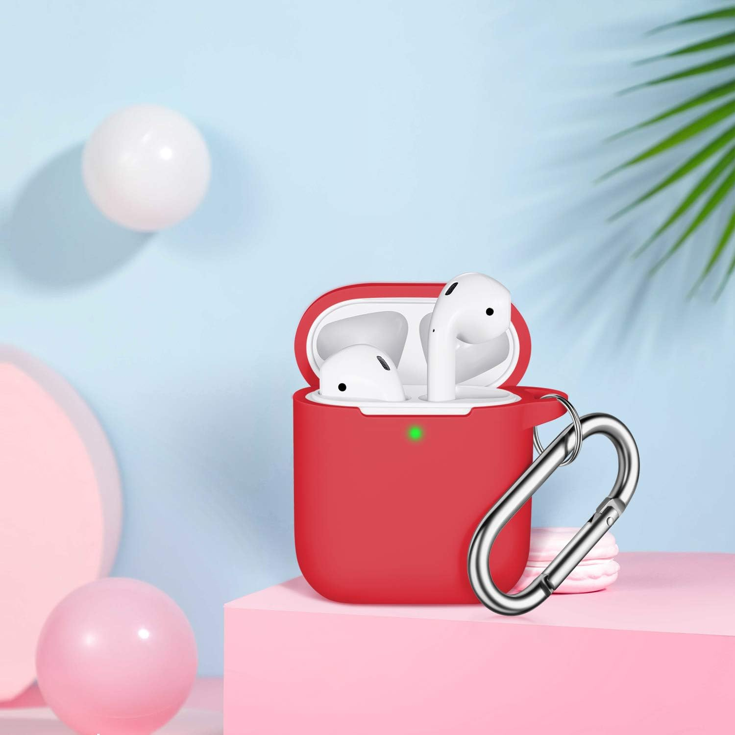 Rotes AirPods-Etui mit weißen Ohrhörern. Silberner Haken befestigt. Pinke und weiße Kugeln auf blauem und pinkem Hintergrund.