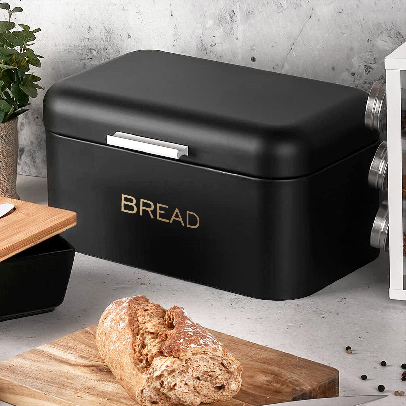 Eine schwarze Brotdose mit dem Wort BROT, ein Brotlaib und ein Schneidebrett.