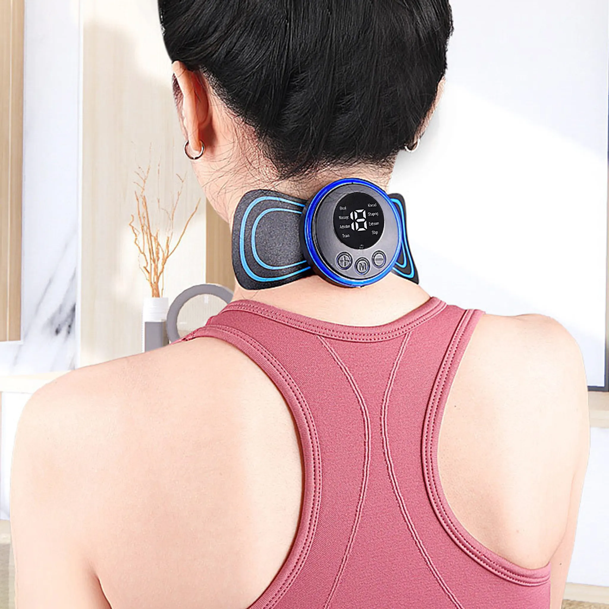 Eine Frau mit pinkem Oberteil trägt ein Nackenmassagegerät. Das Gerät ist schwarz und blau mit Digitalanzeige.