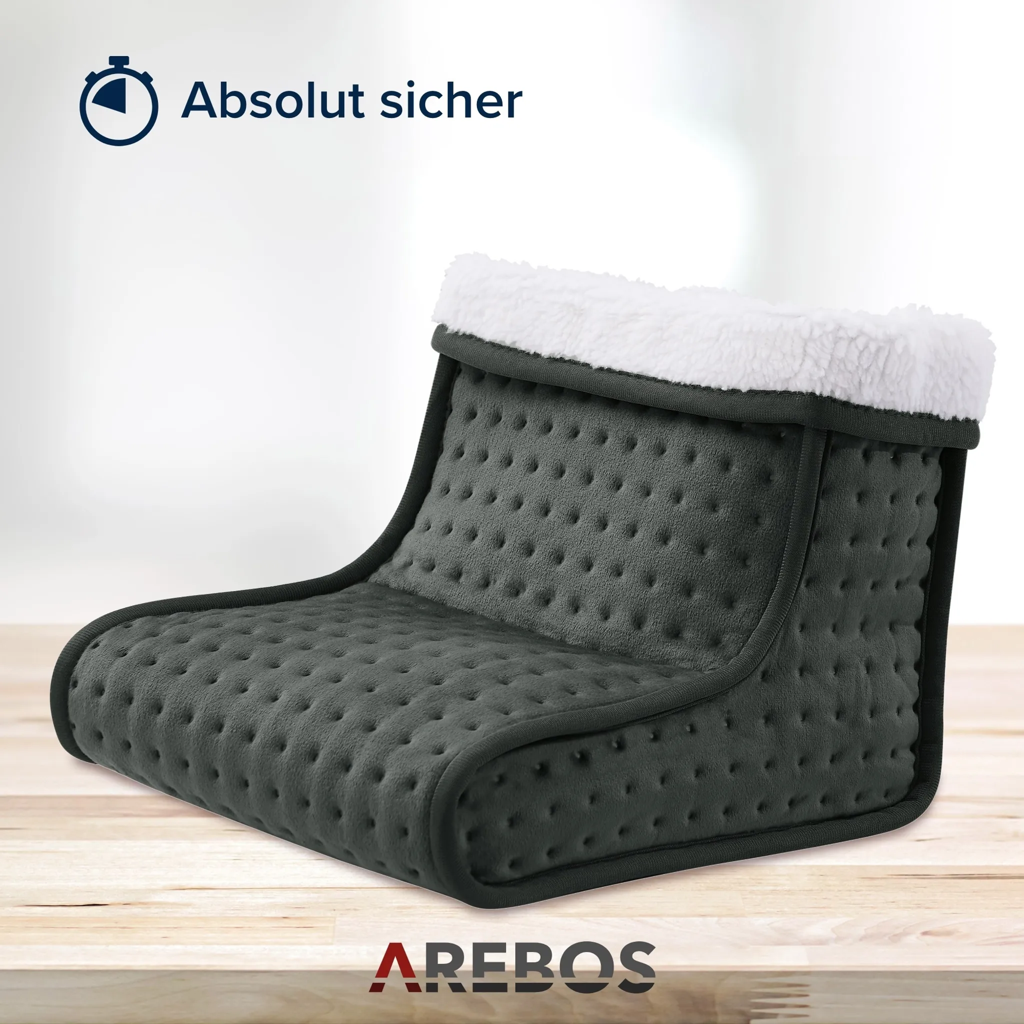 Ein grauer Fußwärmer mit weißem, flauschigem Besatz auf einer hellen Holzoberfläche. Der Text oben lautet: 'Absolut sicher'.