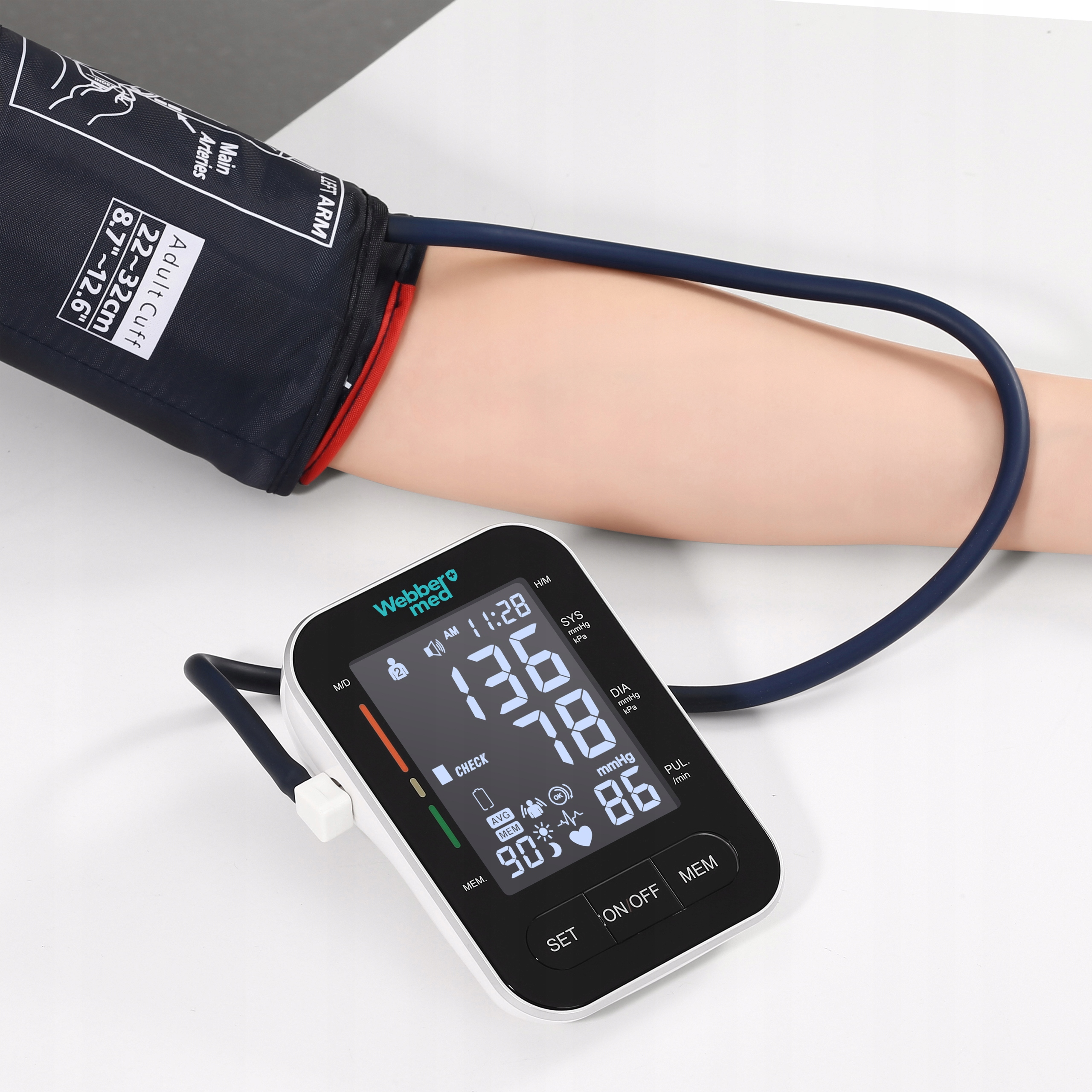 Ciśnieniomierz leży na stole z ramieniem w mankiecie. Monitor wyświetla cyfry. Ramię jest blade.