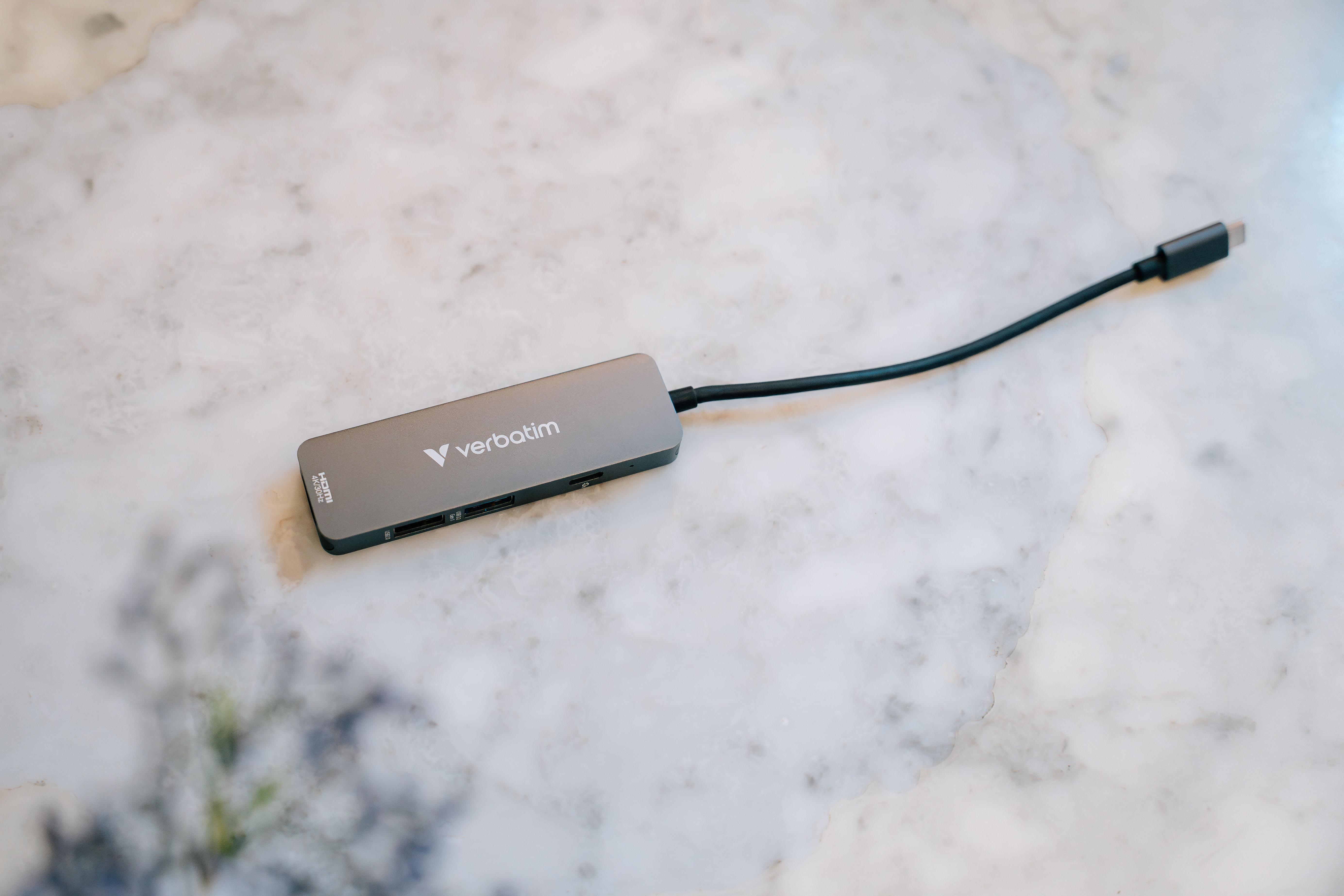 Grauer Verbatim USB-C-Hub auf Marmoroberfläche. Der Hub hat ein schwarzes Kabel.