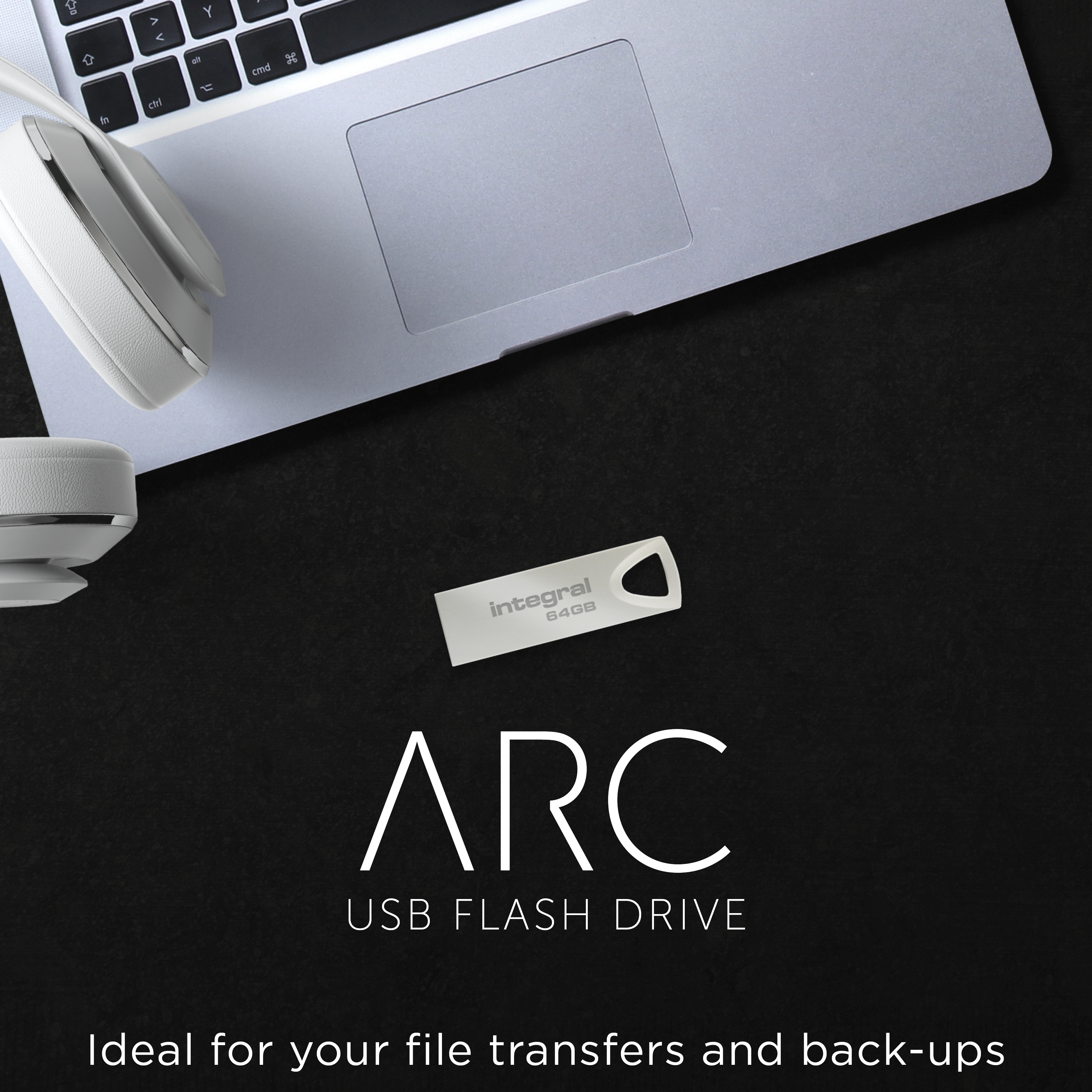 A laptop, headphones, and a USB drive are on a black surface. The USB drive reads 'Integral 64GB ARC USB FLASH DRIVE'.