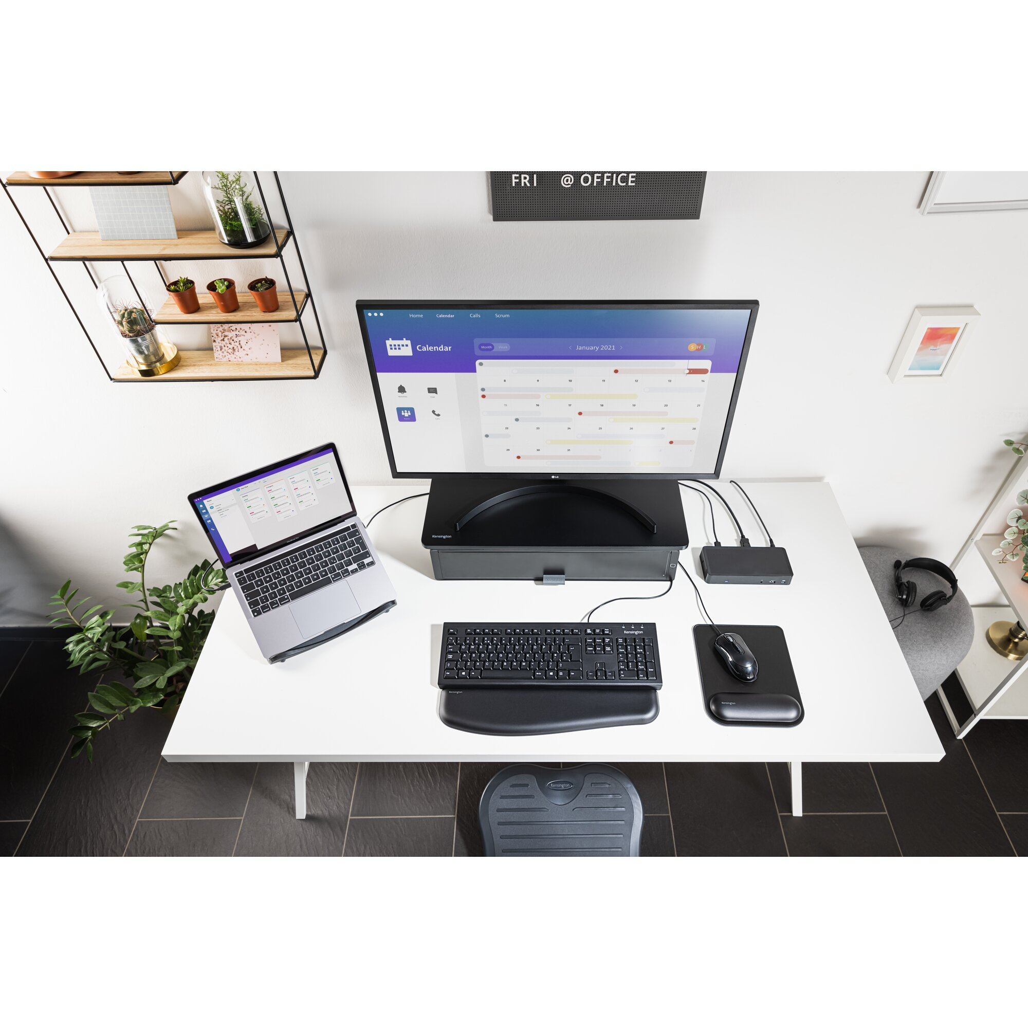 Nowoczesne stanowisko biurowe z monitorem wyświetlającym kalendarz, laptopem, klawiaturą, myszą i innymi akcesoriami.