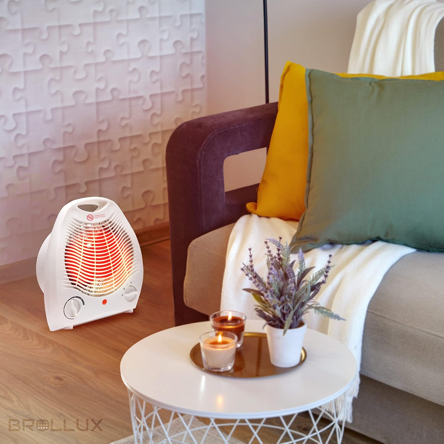 Ein weißer Elektroheizer steht auf einem Holzboden. Ein Tisch mit Kerzen und einer Pflanze steht neben einem Sofa mit Kissen und Decke.