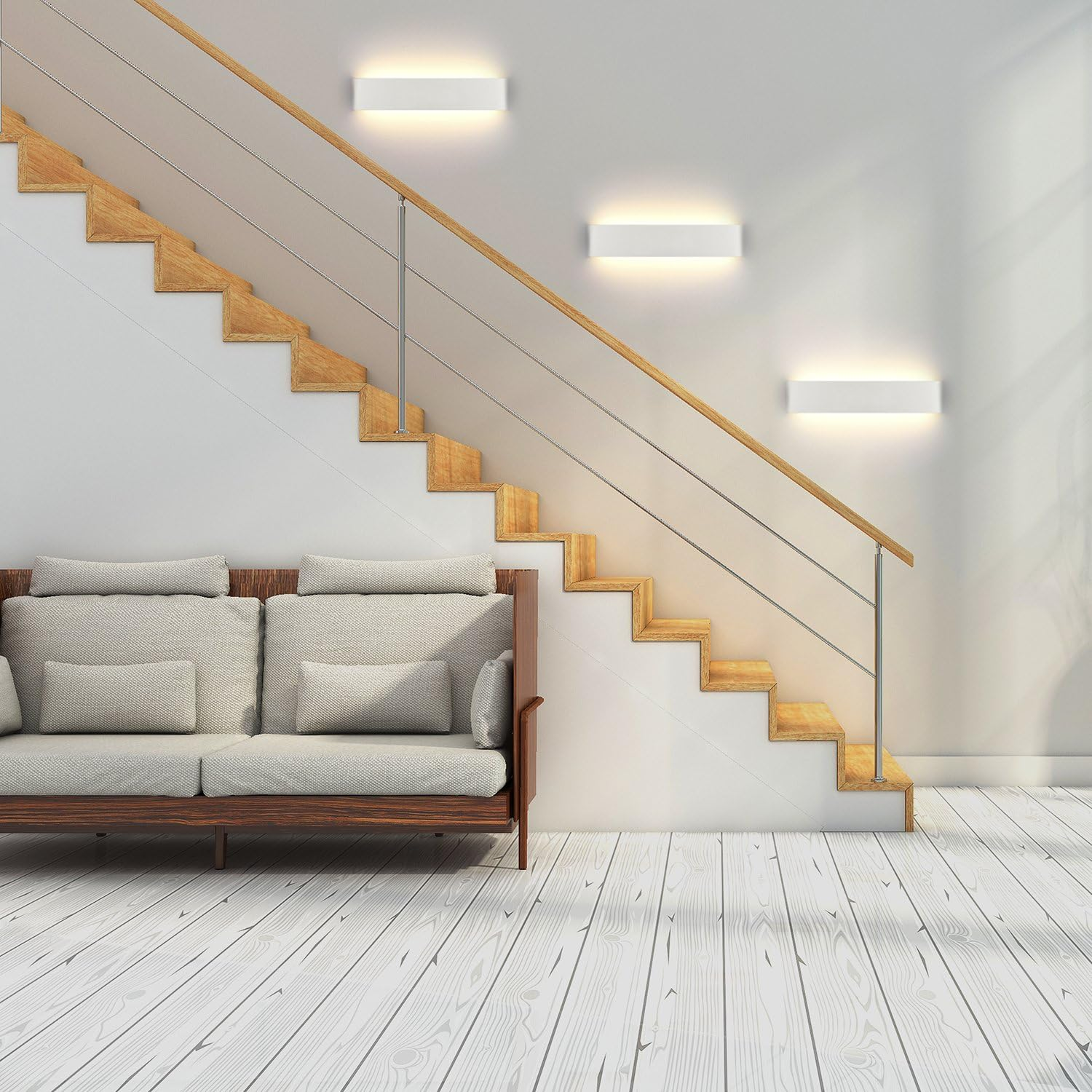 Holztreppe mit weißen Wänden. Vorne steht ein Sofa, und an der Wand sind Lichter. Hellfarbiger Holzboden.