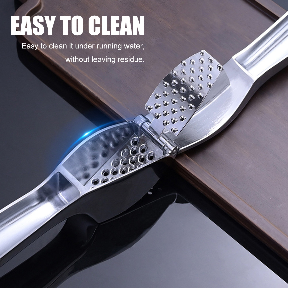 Eine Knoblauchpresse aus Metall auf einer Holzoberfläche. Der Text lautet 'EASY TO CLEAN'. Die Presse ist geöffnet.