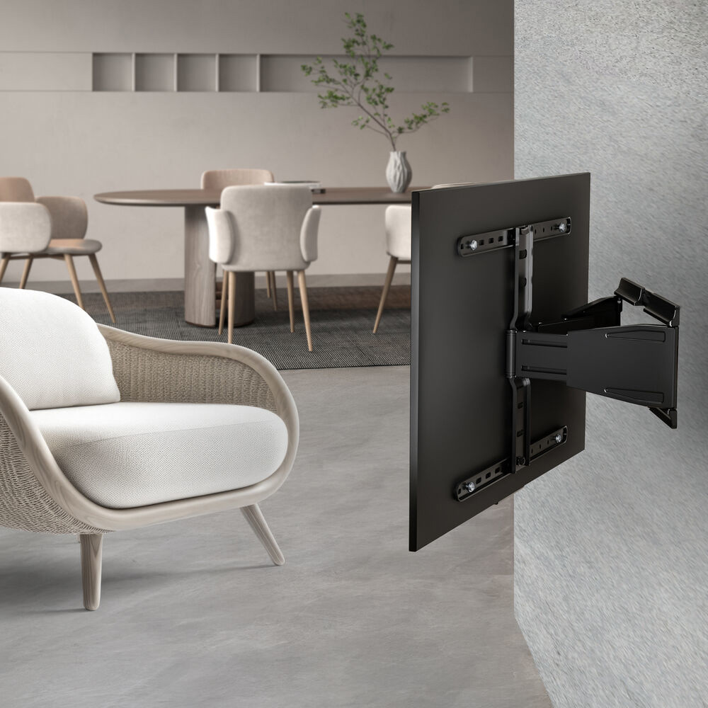 Ein modernes Wohnzimmer mit einem wandmontierten schwarzen Fernseher und einem weißen Sessel. Im Hintergrund sind ein Esstisch und Stühle zu sehen.