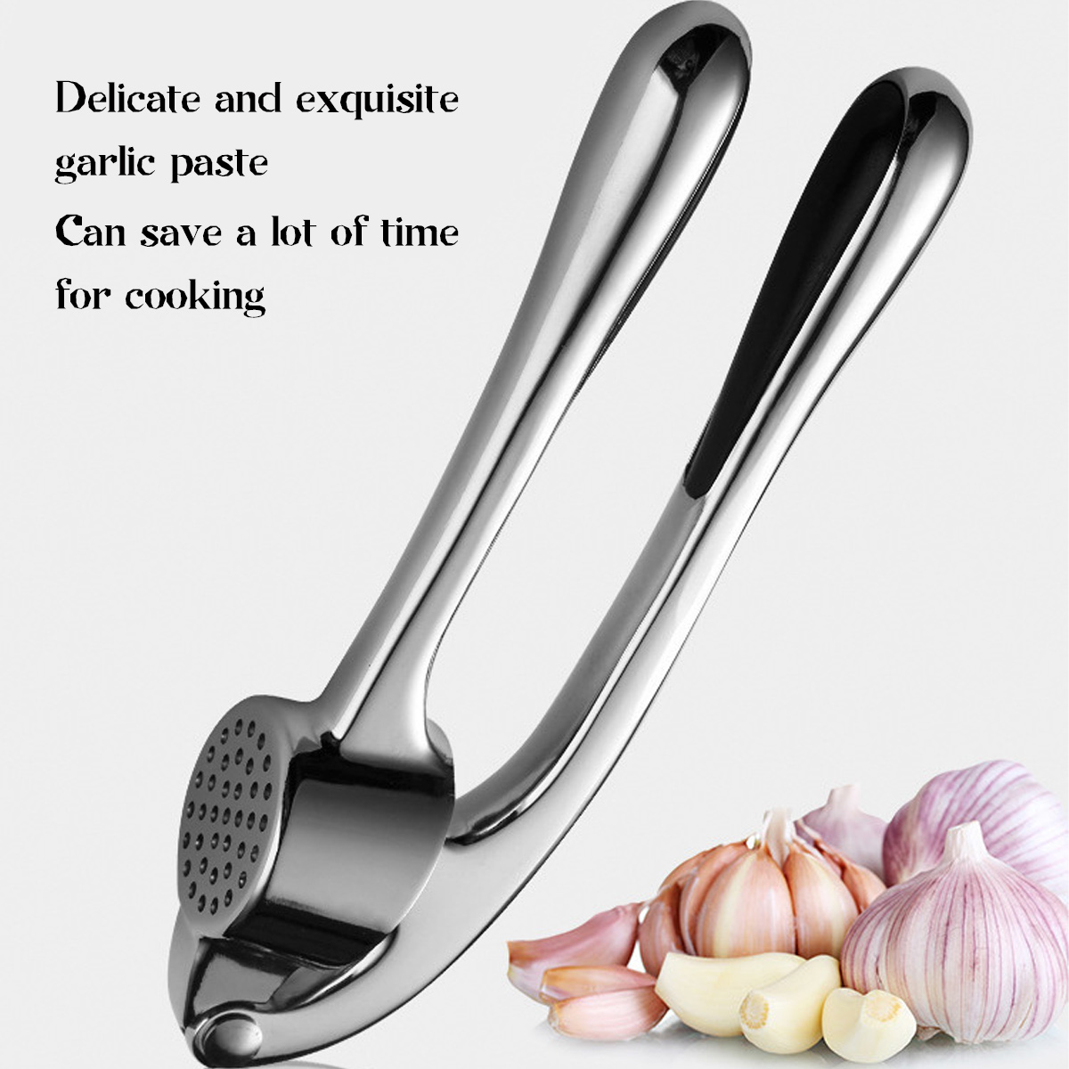 Eine glänzende Knoblauchpresse mit Knoblauchzehen und -knollen im Hintergrund. Text: zarte und exquisite Knoblauchpaste, spart Zeit beim Kochen.