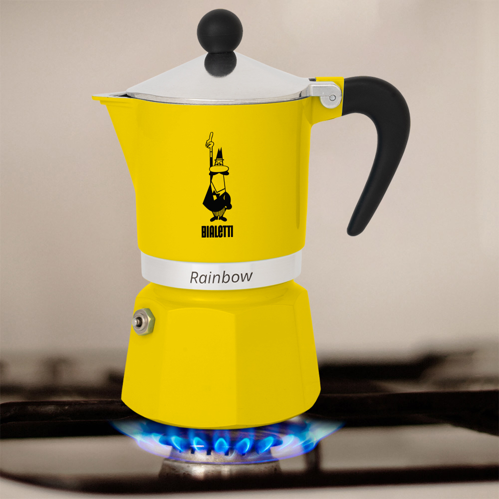 Ein gelber Bialetti Rainbow Espressokocher auf einem Gasbrenner. Der Kocher steht auf einer blauen Flamme.