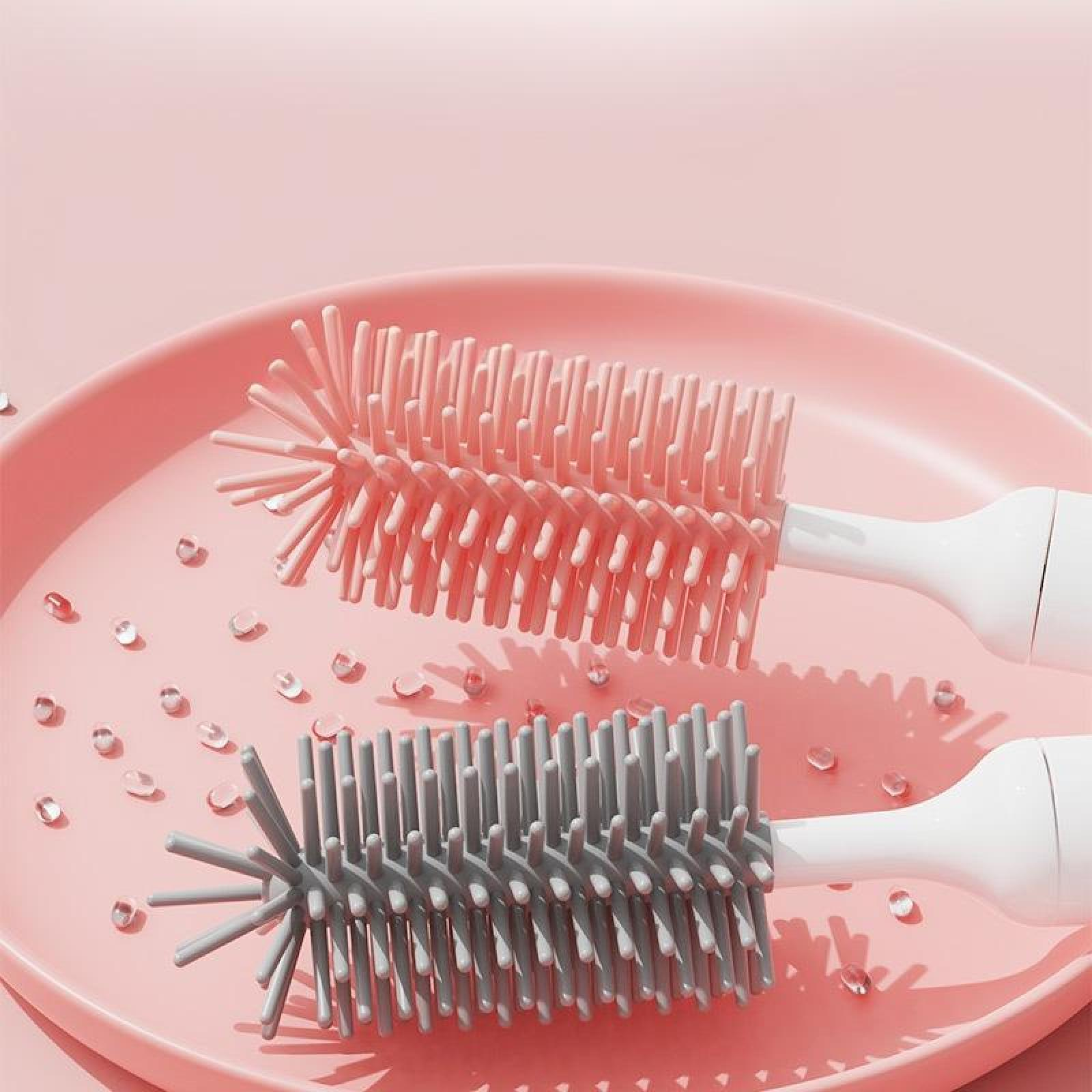 Zwei Flaschenbürsten, rosa und grau, auf einem rosa Teller. Wassertropfen verstreut. Weiße Griffe.
