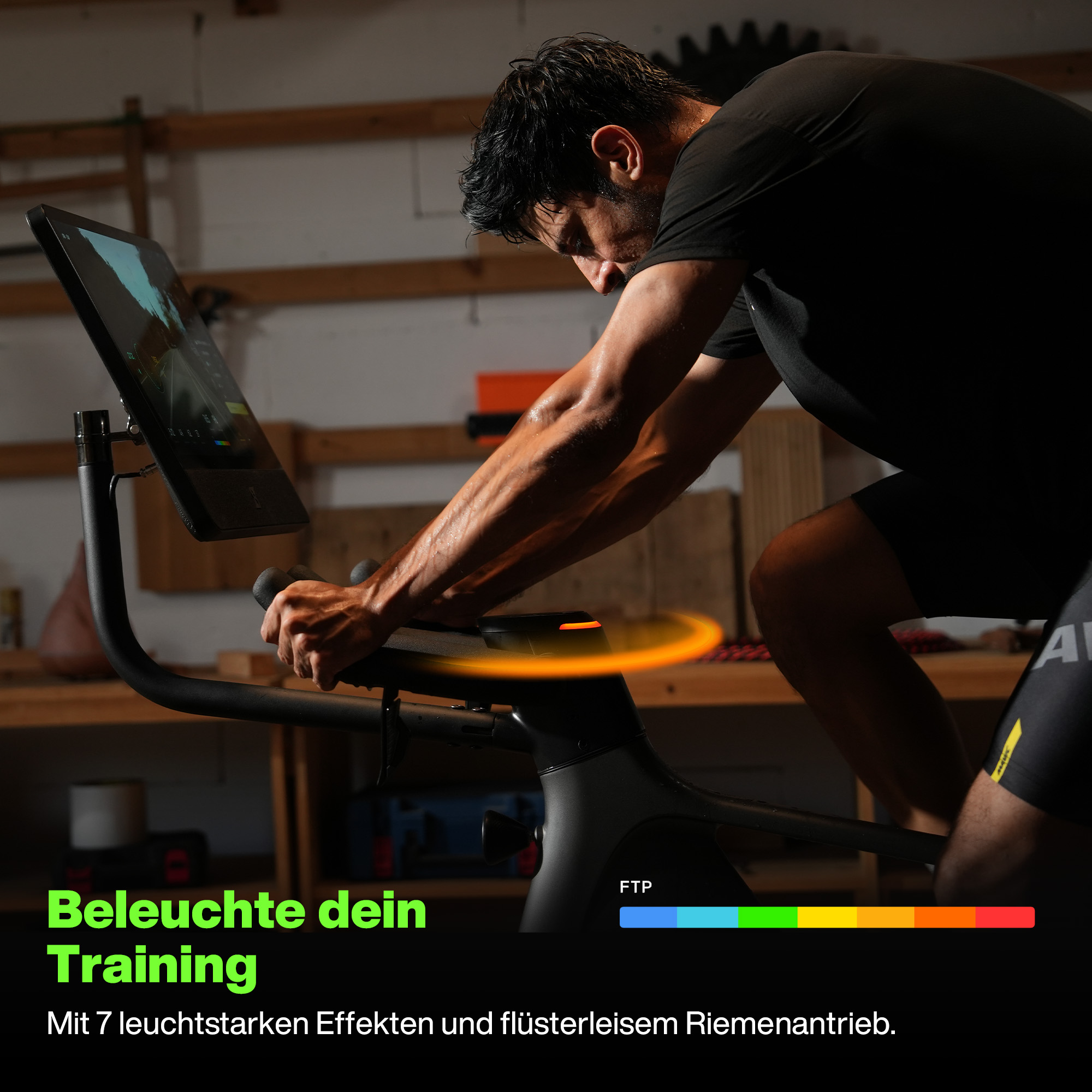 Mann auf einem stationären Fahrrad. Er schwitzt. Das Fahrrad hat einen Bildschirm. Text: 'Beleuchte dein Training'.