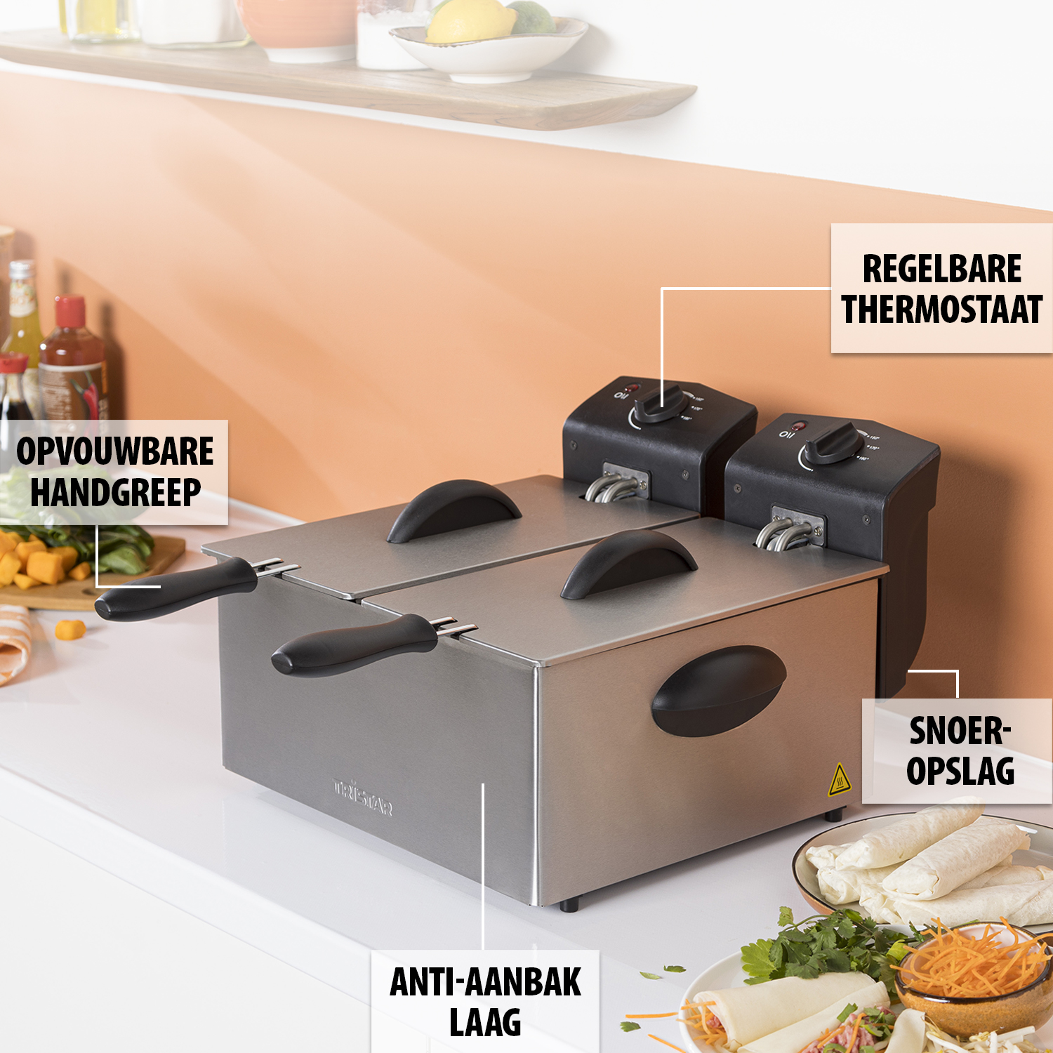 Frytownica ze stali nierdzewnej z czarnymi uchwytami i pokrętłami. Żywność, w tym wrapy, znajduje się na białej powierzchni.