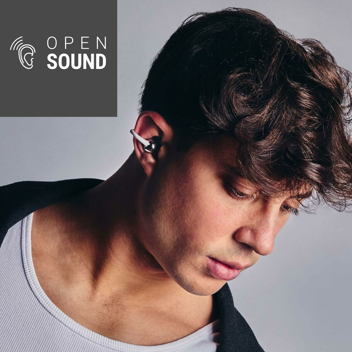 Un uomo con un auricolare, che guarda in basso. Le parole 'OPEN SOUND' e un logo a onda sonora sono in alto a sinistra.