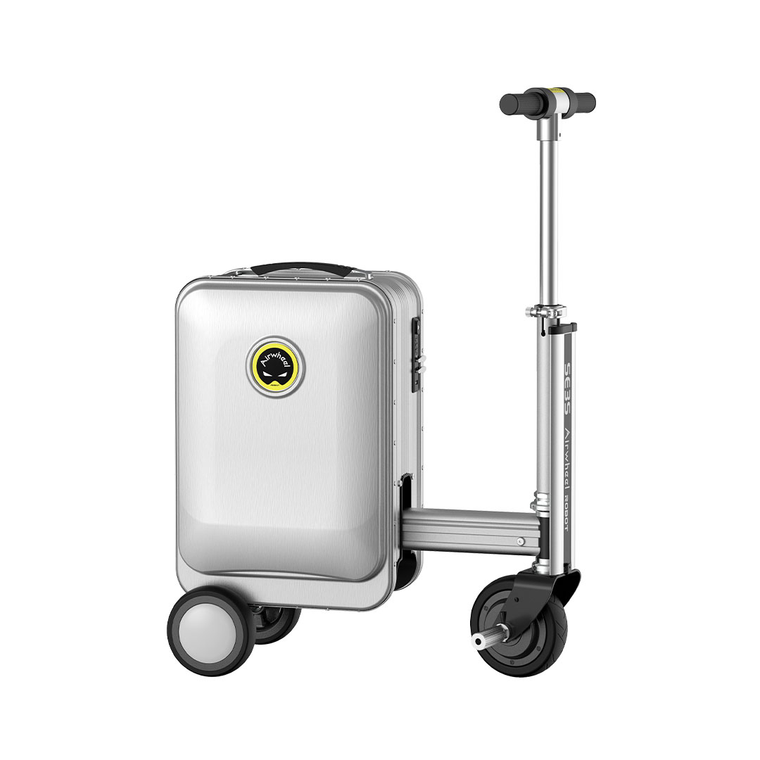 Gümüş valiz, scooter takılı. Valizin tekerlekleri ve logosu var. Scooter'ın bir gidonu ve tekerleği var.