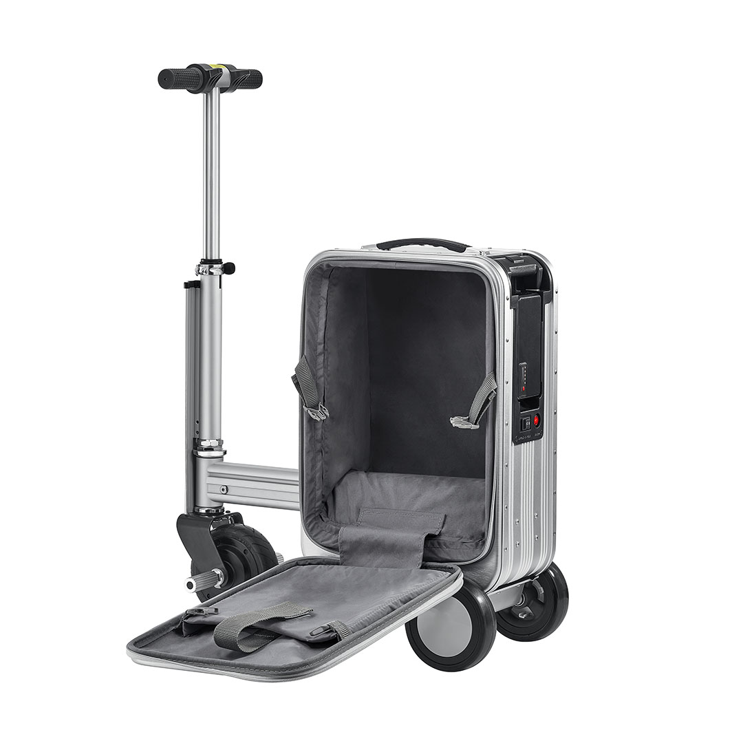 Açık kapaklı gümüş bir bavul ve yerleşik bir scooter. Bavulun içi gri. Scooter solda.