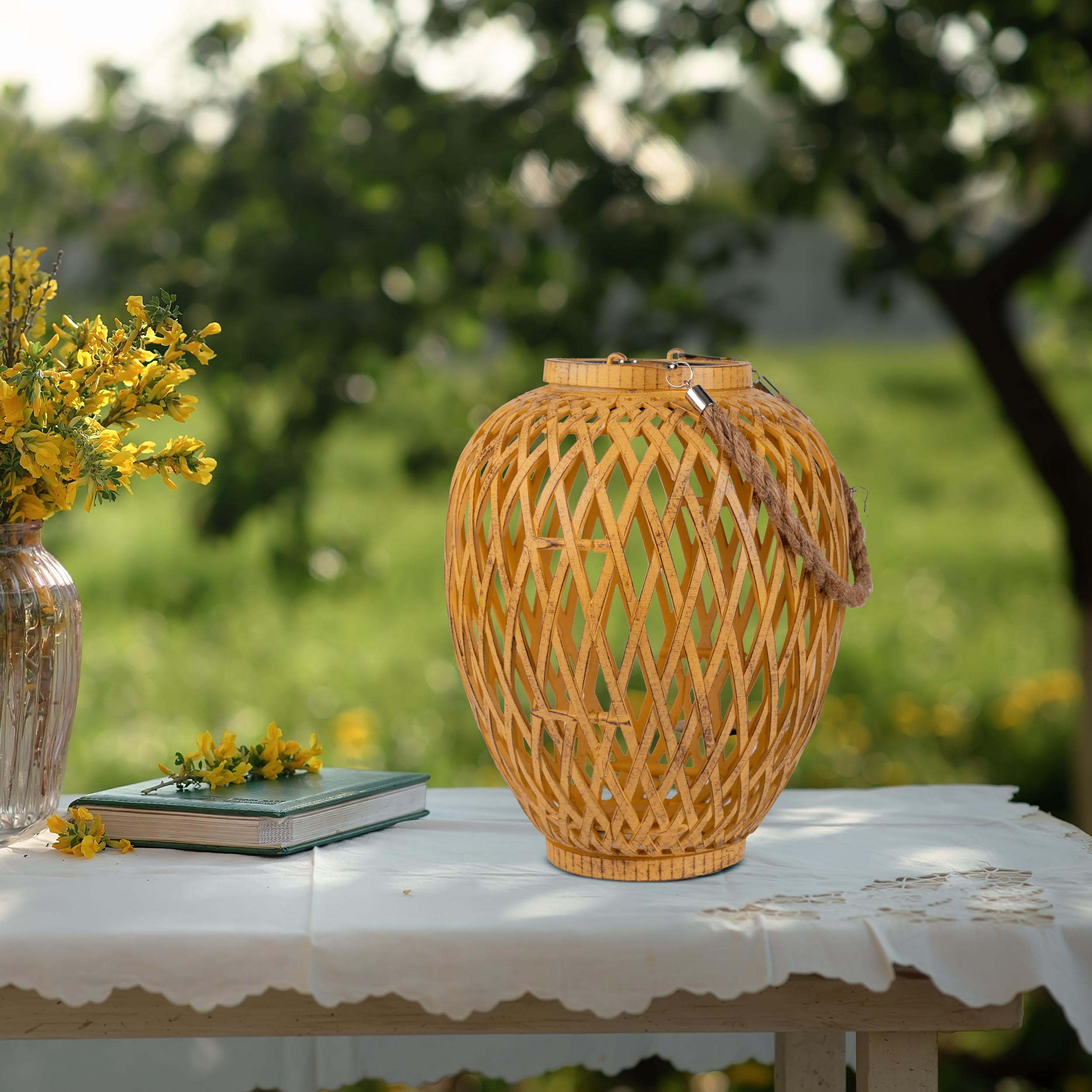 Eine gewebte Laterne, ein Buch und Blumen auf einem weißen Tisch. Grüner Hintergrund.