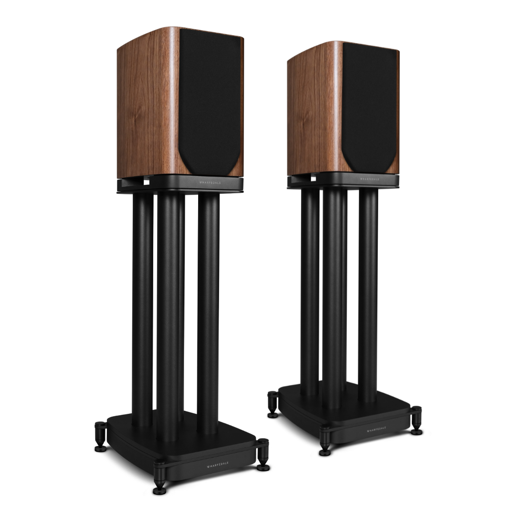 Twee speakers. Houten kisten met zwarte voorkanten staan op zwarte statieven met drie poten. De statieven staan op vierkante zwarte voetstukken.