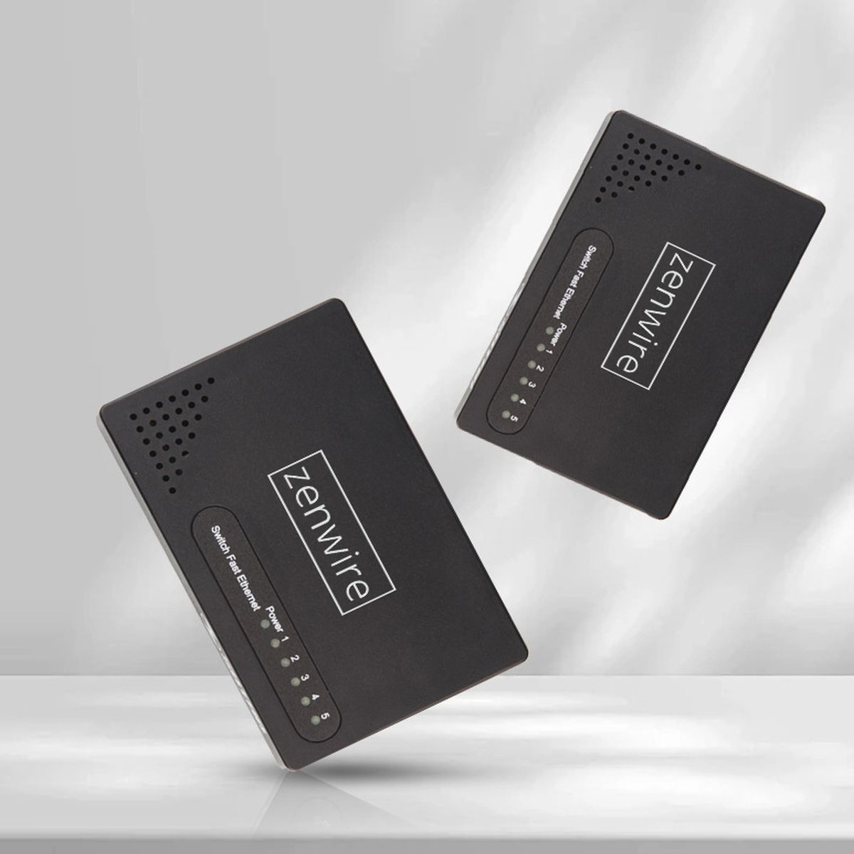 Dwa czarne przełączniki sieciowe Zenwire na jasnym tle. Każdy przełącznik wyświetla 'Switch Fast Ethernet' i wskaźniki zasilania.