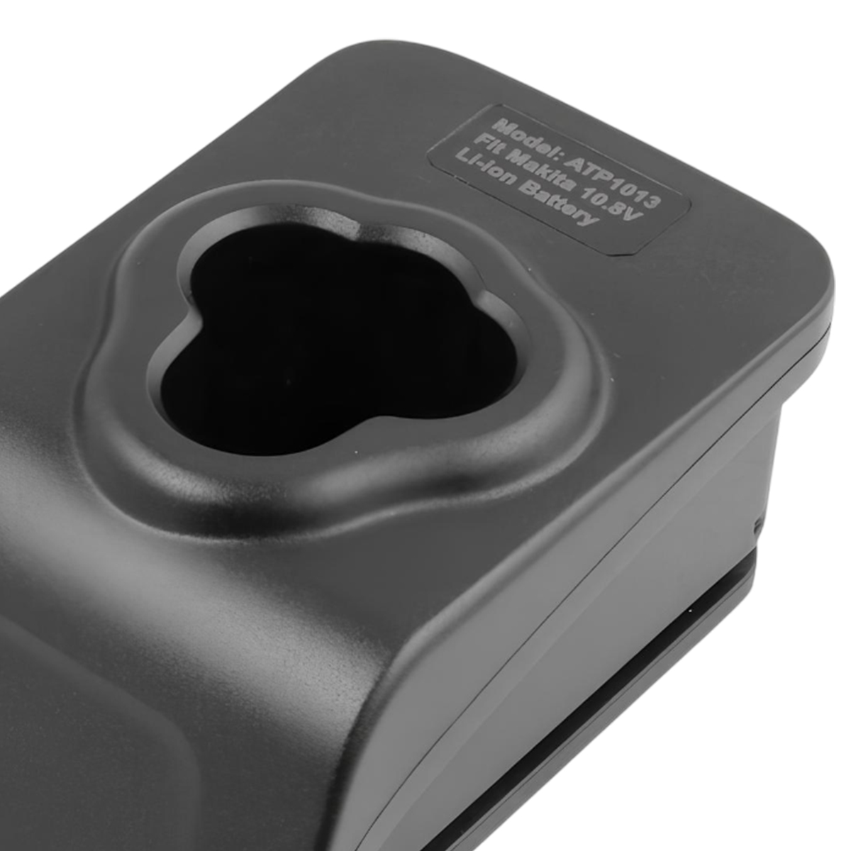 Un cargador de batería negro para baterías de iones de litio Makita de 10,8 V. Tiene un enchufe de tres lóbulos y texto con el número de modelo.
