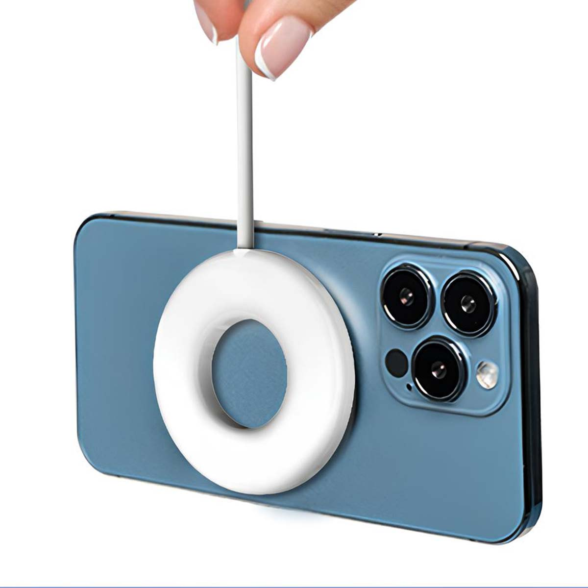 Eine Hand hält ein weißes kreisförmiges Ladegerät über einem blauen Telefon. Das Telefon hat eine Dreifach-Kamera. Das Ladegerät ist mit dem Telefon verbunden.