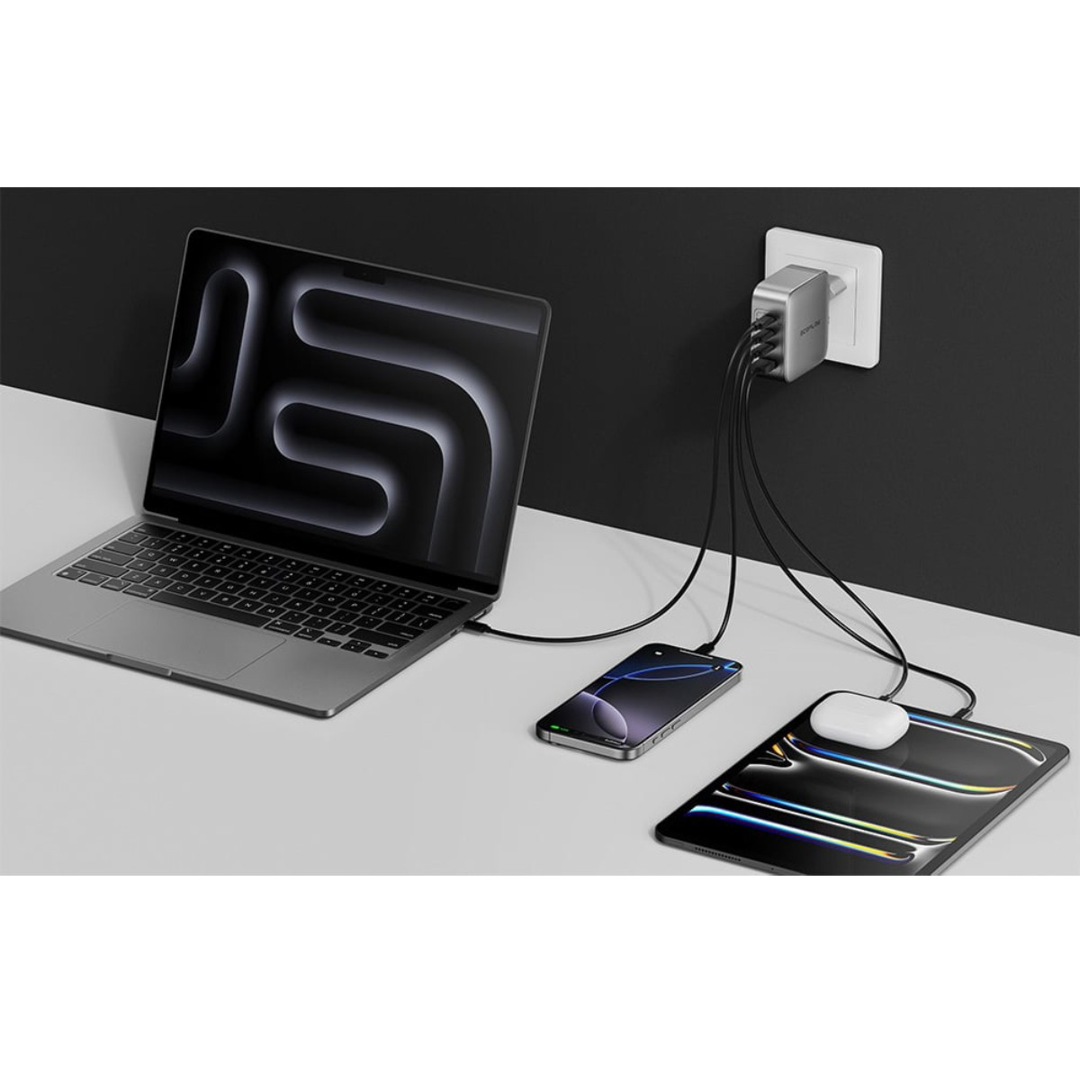Ładowanie laptopa, telefonu, tabletu i słuchawek AirPods. Urządzenia są podłączone do zasilacza wpiętego do gniazdka ściennego.