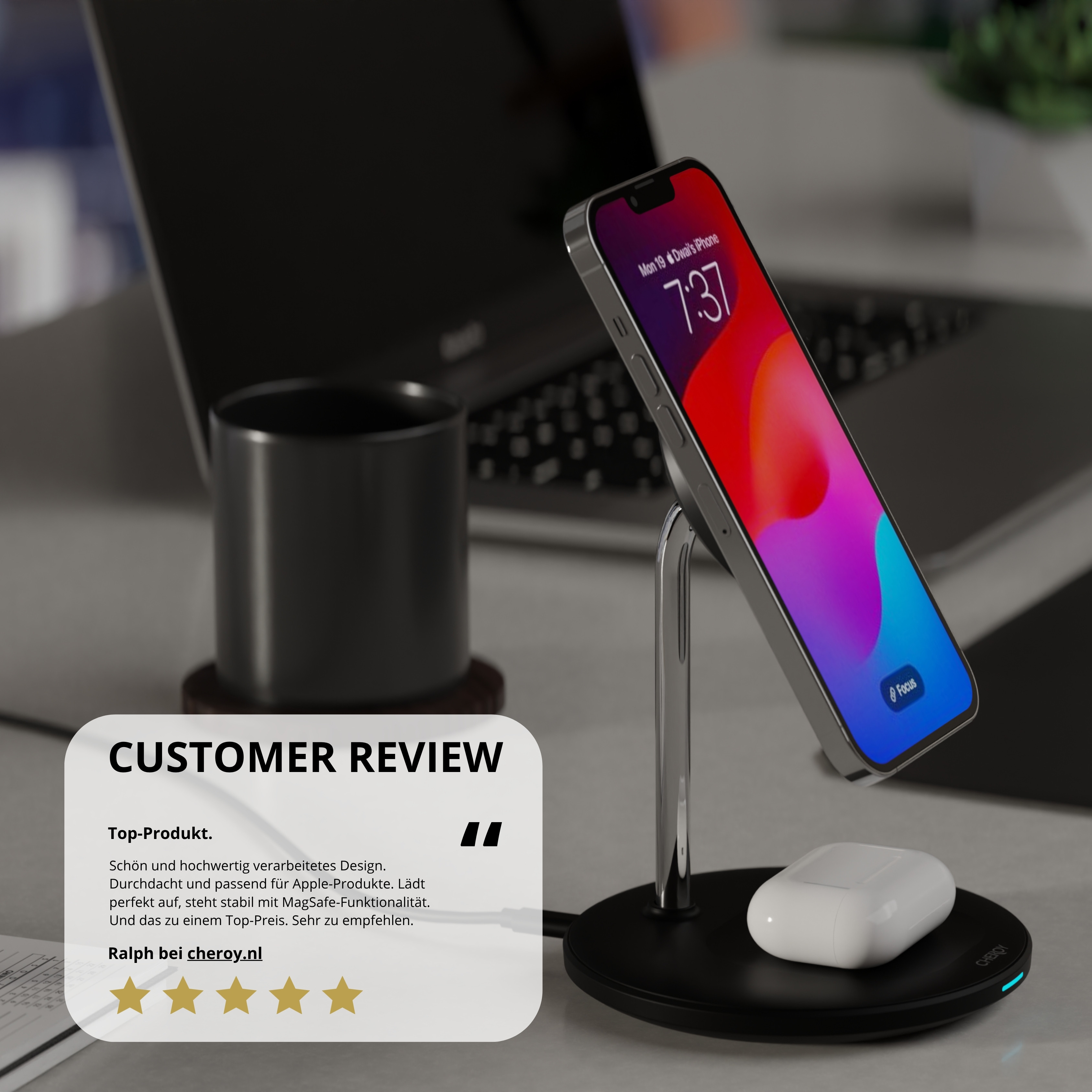Ein iPhone steht auf einem Ständer, mit AirPods, einer schwarzen Basis und einem Laptop im Hintergrund. Eine Kundenrezension ist sichtbar.