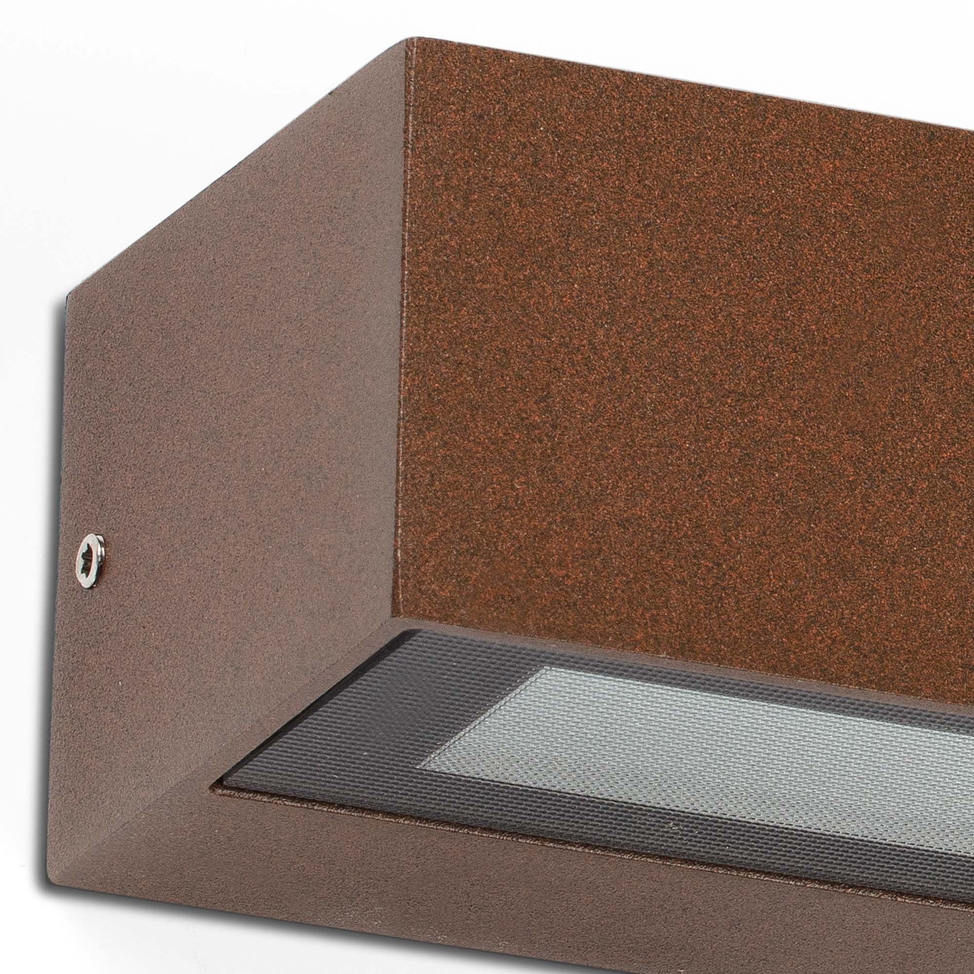 Eine rechteckige Außenleuchte aus Bronze ist an einer weißen Wand befestigt. Sie hat ein versenktes Licht.