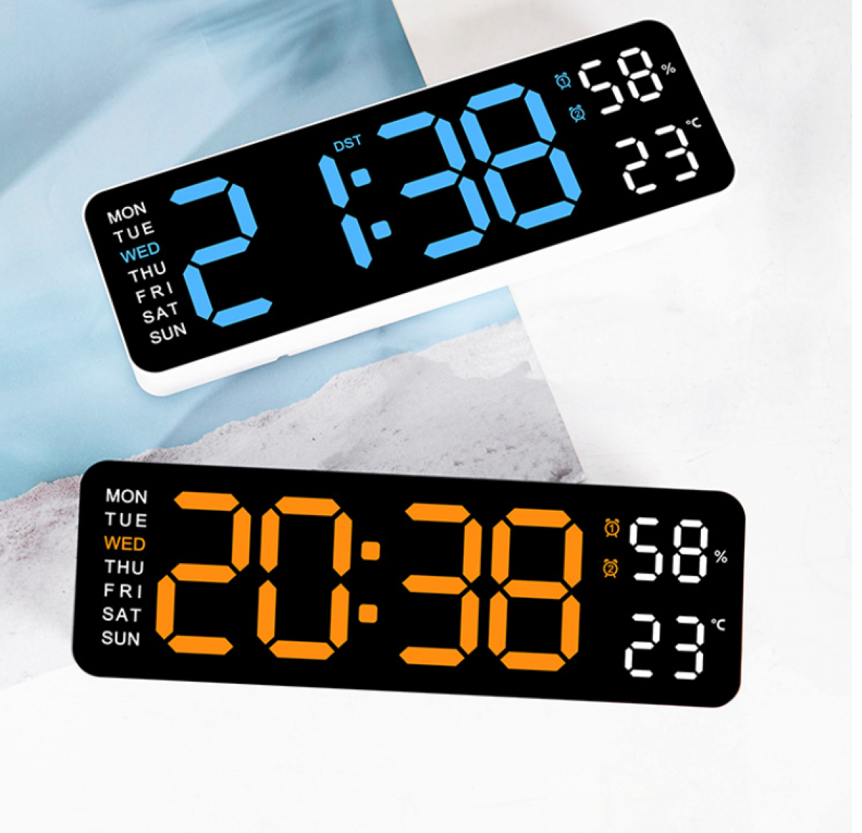 Zwei Digitaluhren mit Zeit-, Feuchtigkeits- und Temperaturanzeige. Eine Uhr zeigt blaue Ziffern auf Weiß, die andere orange auf Schwarz.