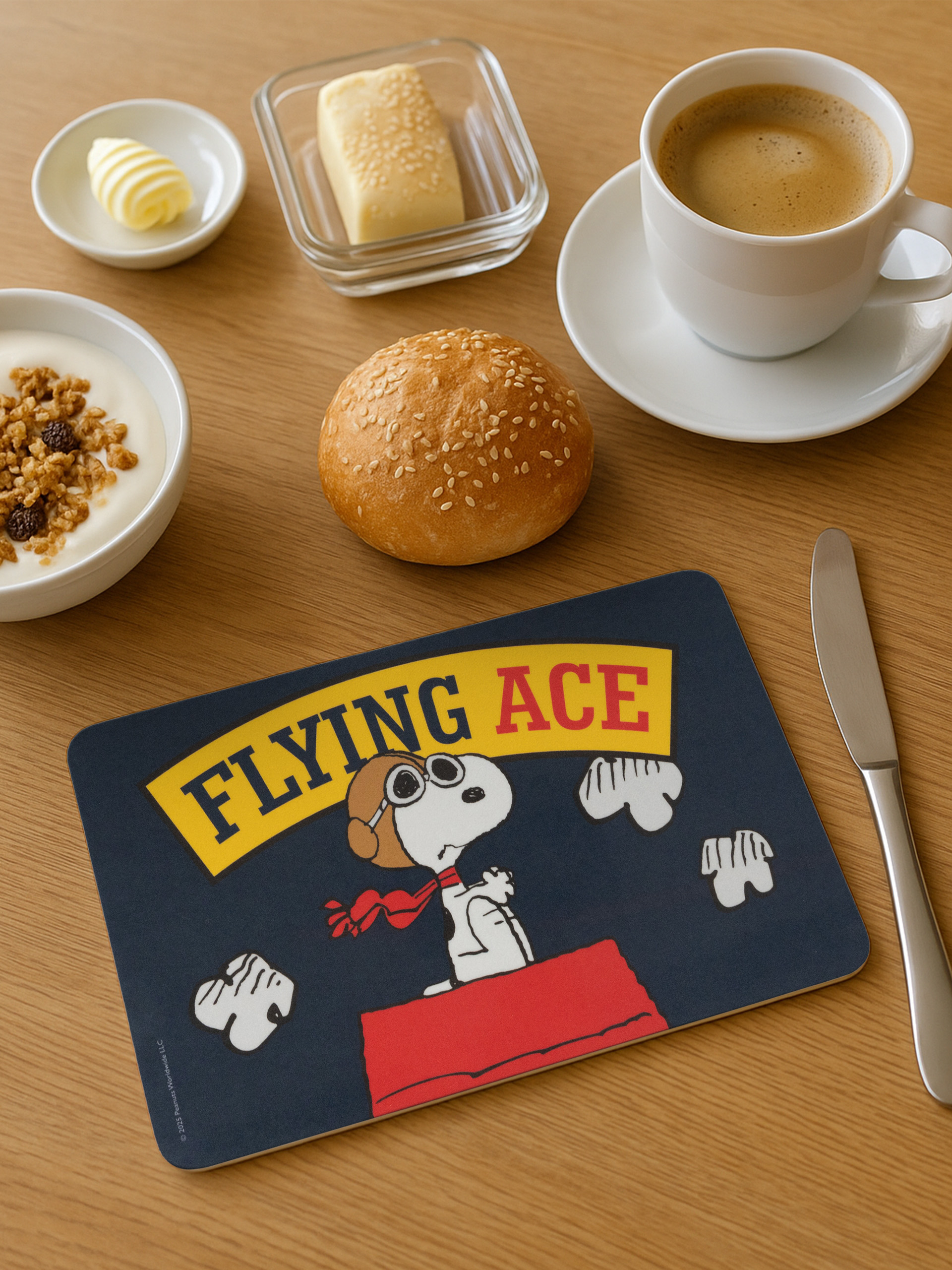 Frühstücksszene mit Kaffee, Brot, Butter, Joghurt und einer Snoopy-Matte.
