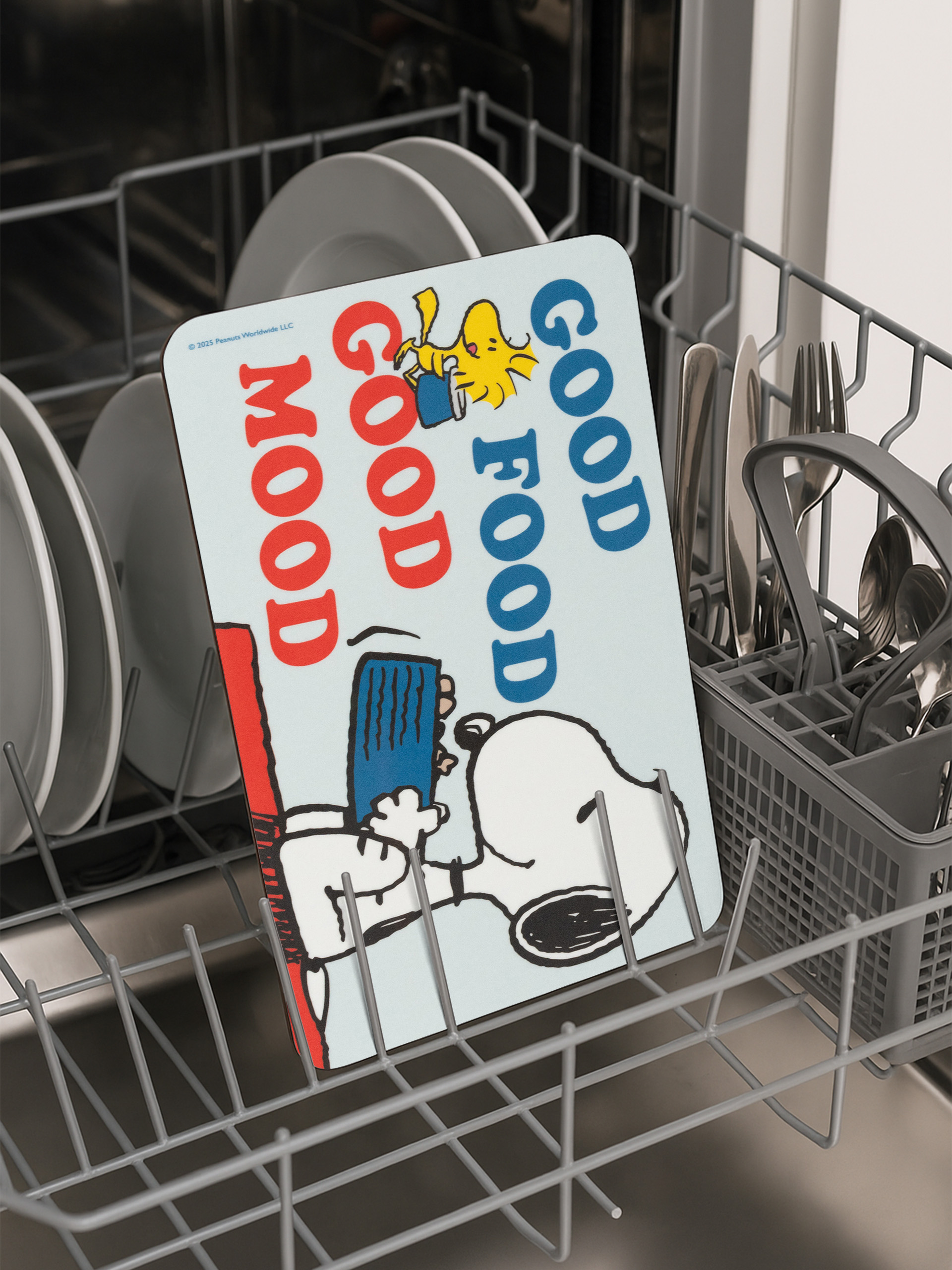 Ein Geschirrspüler mit Tellern und Besteck. Eine Snoopy-Platzmatte mit den Worten 'Good Mood, Good Food' in der Mitte.