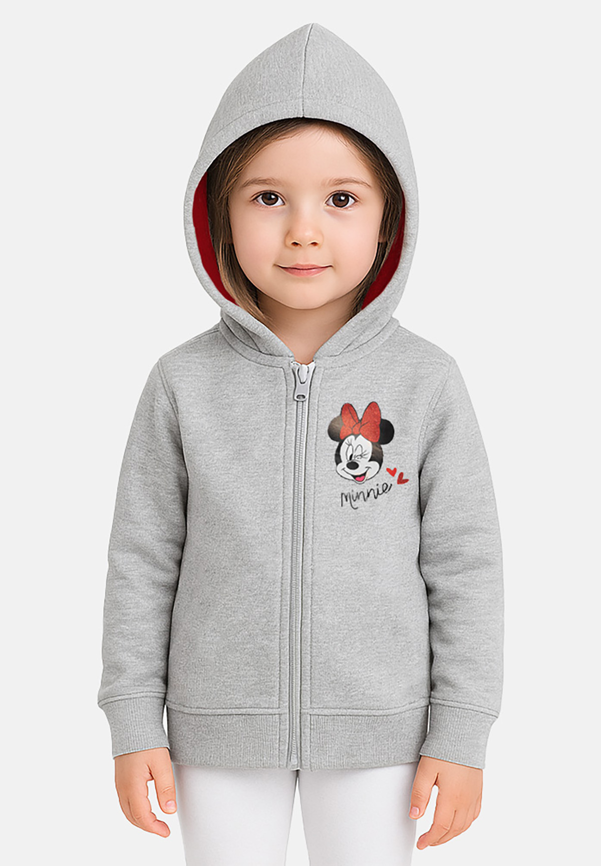 Ein junges Mädchen trägt einen grauen Kapuzenpullover mit einem Minnie Mouse-Design. Die Kapuze hat ein rotes Futter. Sie lächelt.