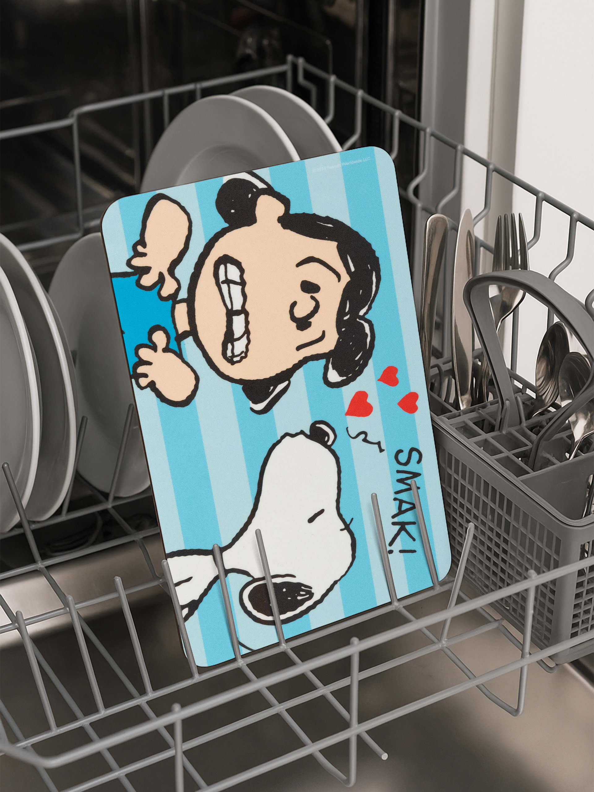 Eine Zeichenteller mit Snoopy befindet sich in einer Spülmaschine. Geschirr und Besteck sind ebenfalls vorhanden.