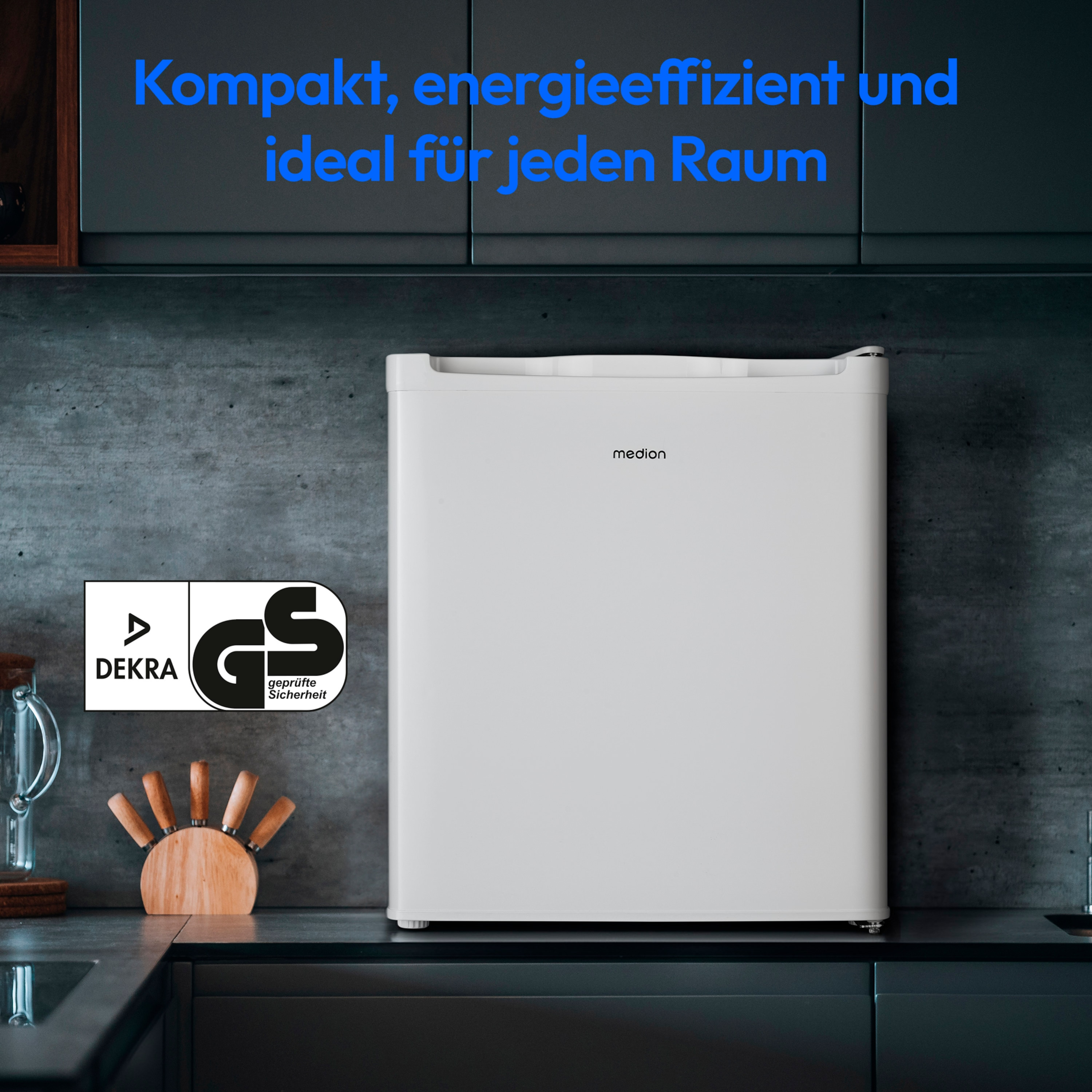 Biała lodówka w otoczeniu kuchennym. Ma nazwę marki 'medion' i tekst 'Kompakt, energieeffizient und ideal für jeden Raum'.