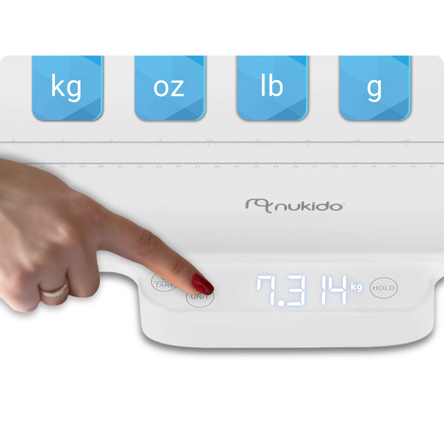 Ręka naciska przycisk jednostki na białej wadze, wyświetlając 7,314 kg. Niebieskie zakładki pokazują kg, oz, lb, g. Waga ma logo 'nukido'.