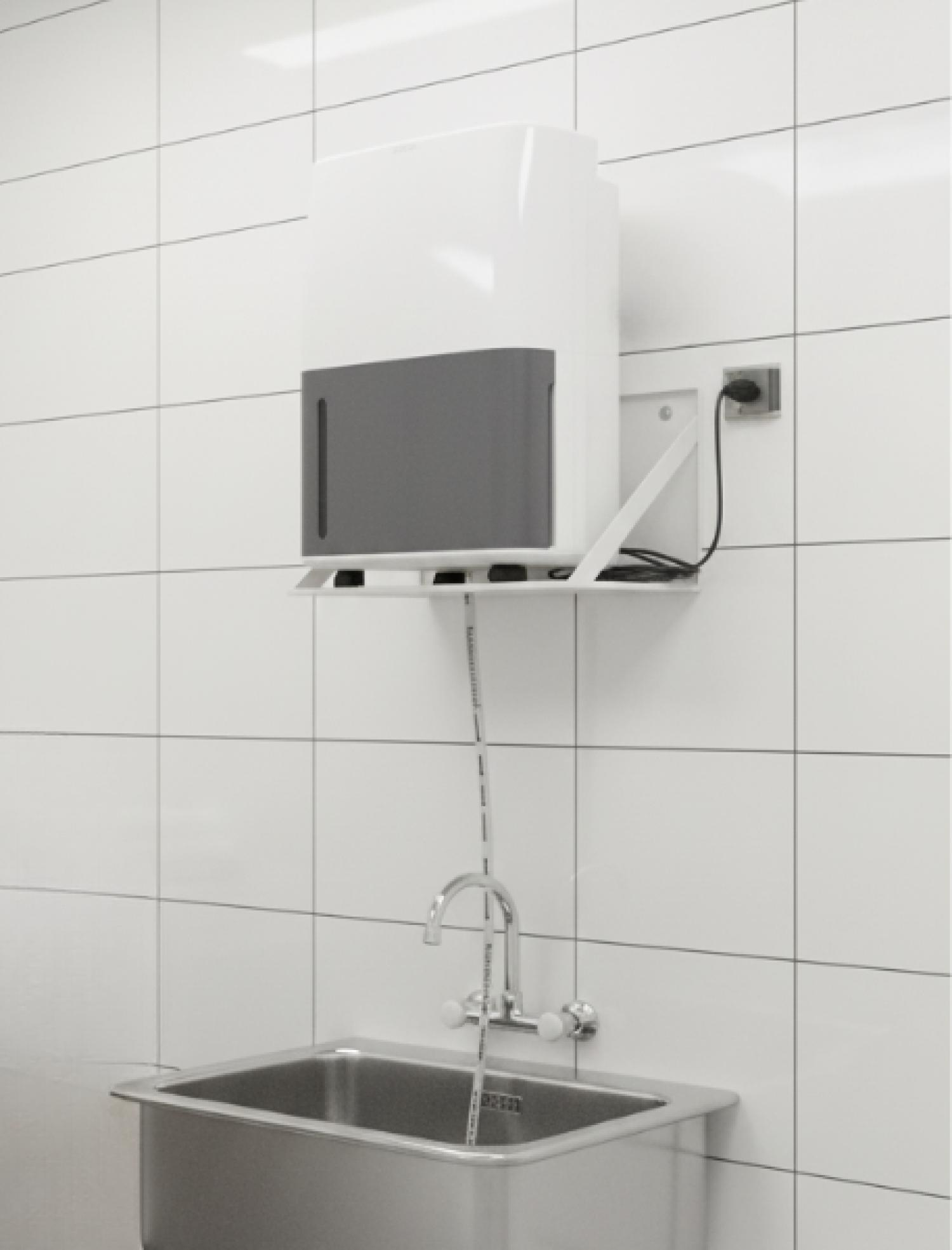 Ein weißer und grauer Händedesinfektionsmittelspender ist über einem Edelstahlbecken mit Wasserhahn montiert. Die Wand ist gefliest.